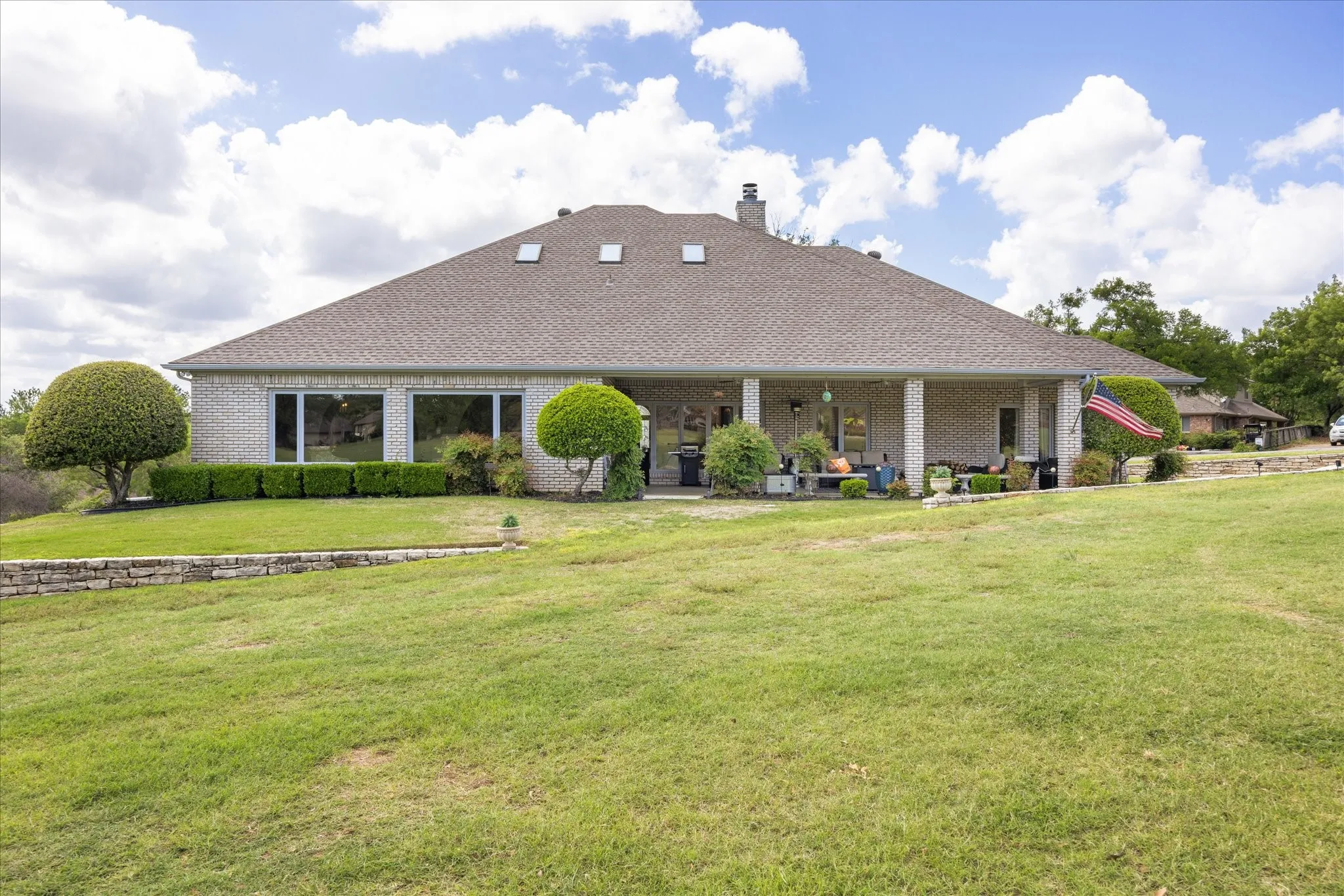 View of front facade featuring a front yard, brick siding, a chimney, and a patio