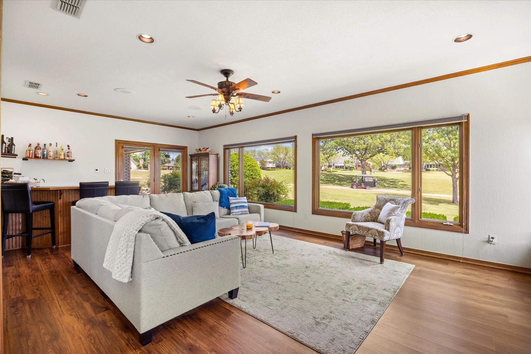 Living room with wood finished floors, ceiling fan, crown molding, and recessed lighting
