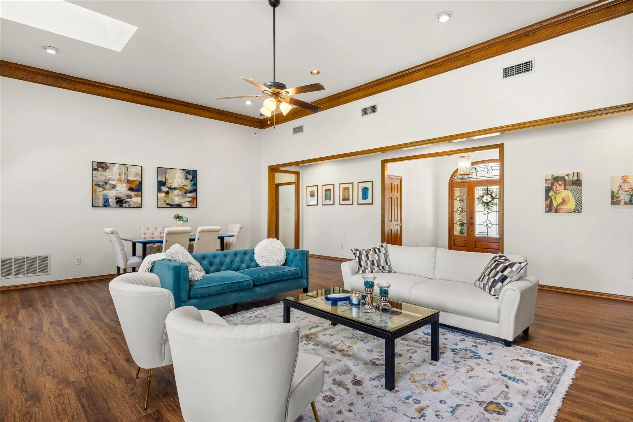 Living room featuring a ceiling fan, dark wood-style flooring, ornamental molding, a skylight, and recessed lighting