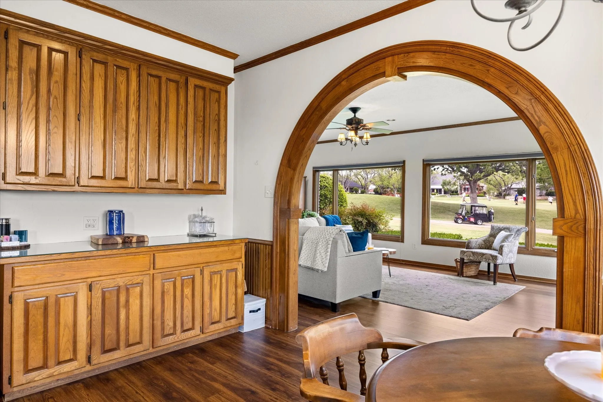 Dining area featuring crown molding, arched walkways, dark wood-style floors, and a ceiling fan