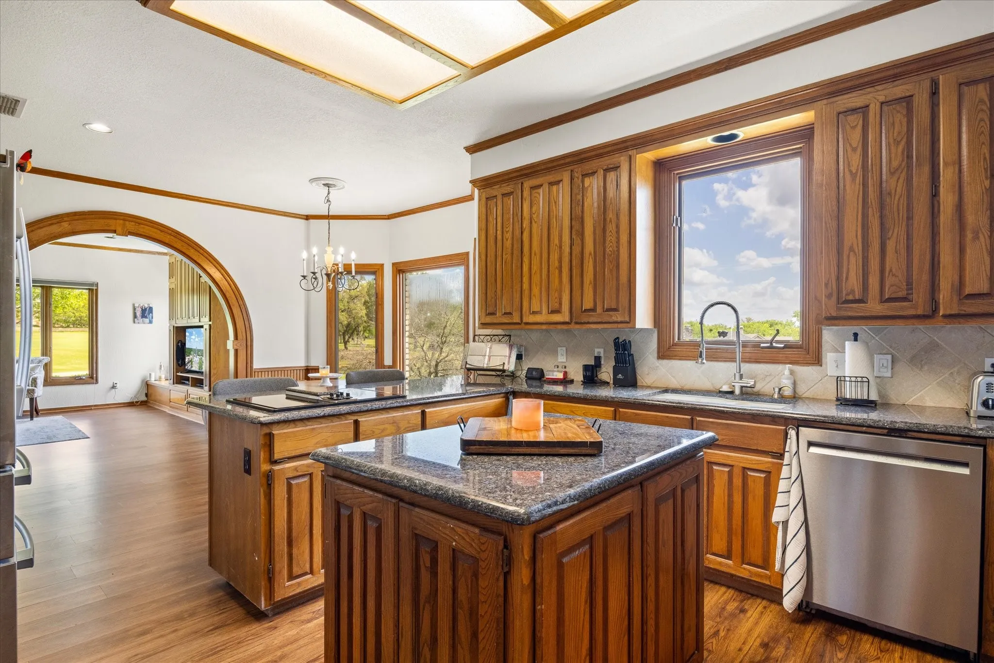 Kitchen featuring a peninsula, wood finish cabinetry, stainless steel appliances, ornamental molding, and dark wood-style flooring