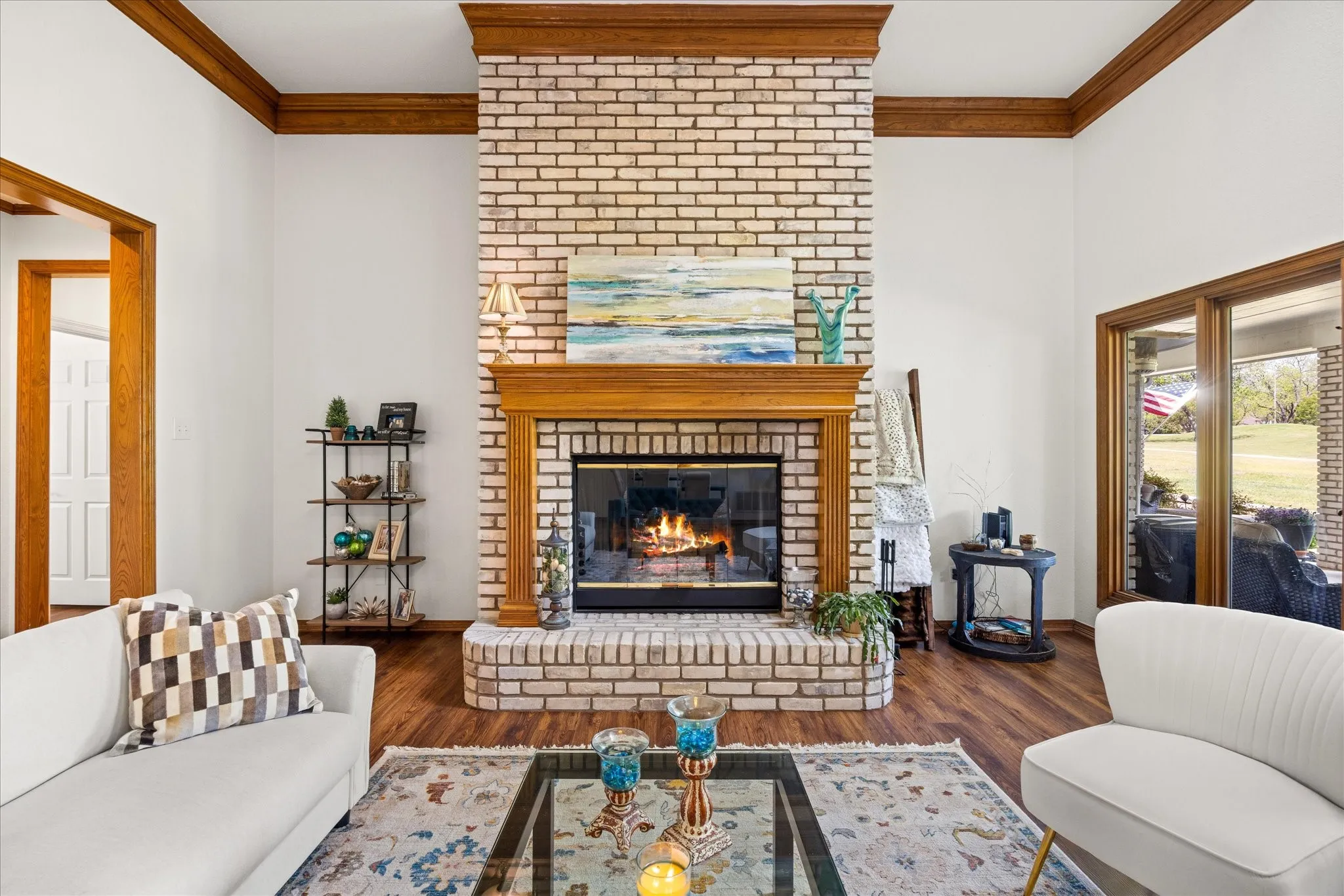 Living room with crown molding, wood finished floors, and a brick fireplace