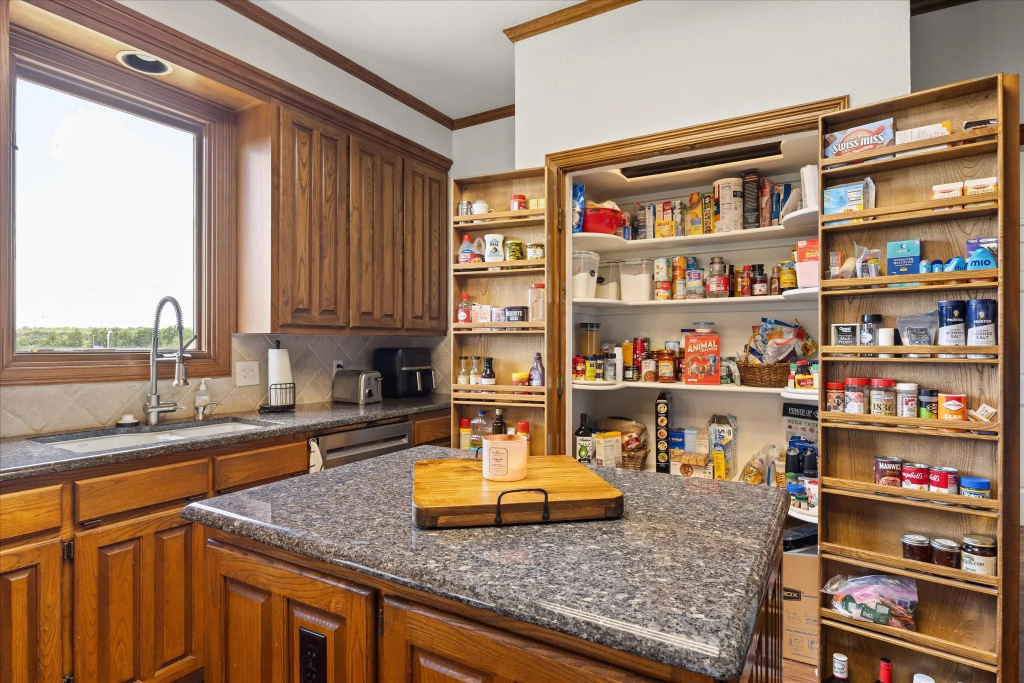 Kitchen featuring a kitchen island, dark stone counters, ornamental molding, tasteful backsplash, and wood finish cabinets