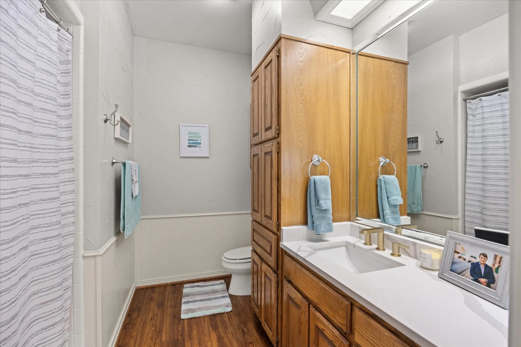 Bathroom featuring a shower with shower curtain, a wainscoted wall, vanity, and dark wood-style flooring