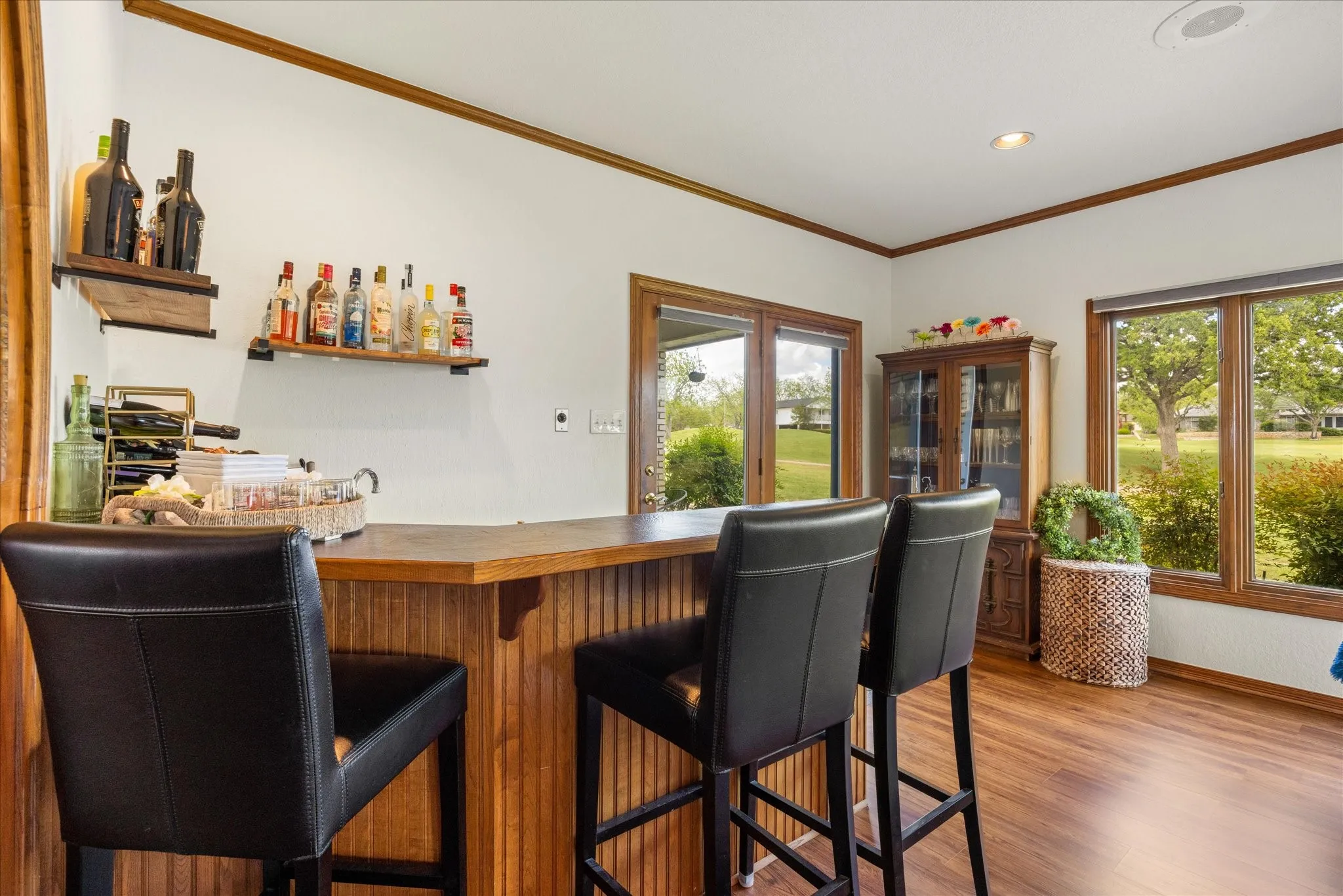Indoor wet bar with light wood finished floors, healthy amount of natural light, crown molding, butcher block countertops, and open shelves