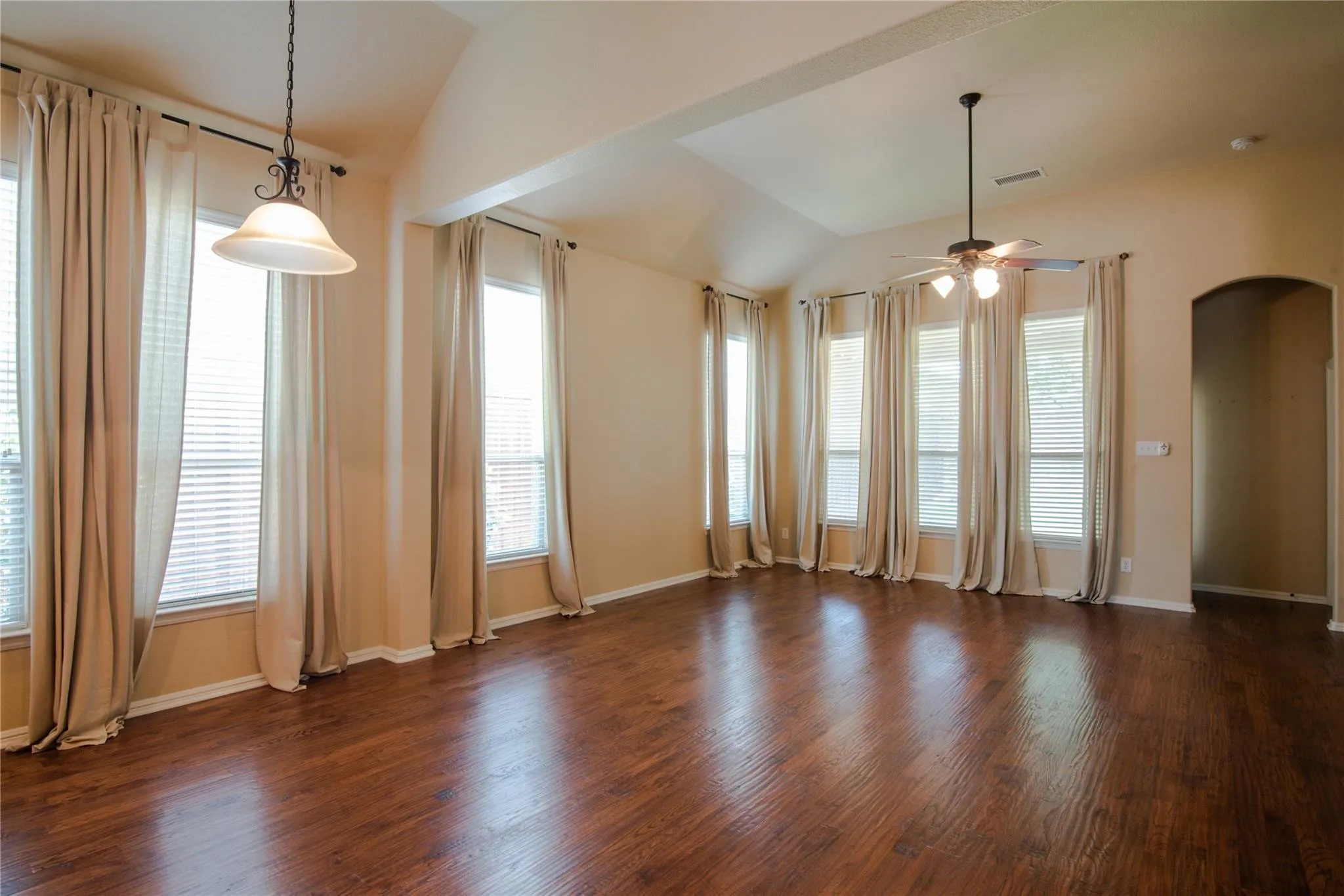 Unfurnished room with dark wood-type flooring, a ceiling fan, vaulted ceiling, and arched walkways