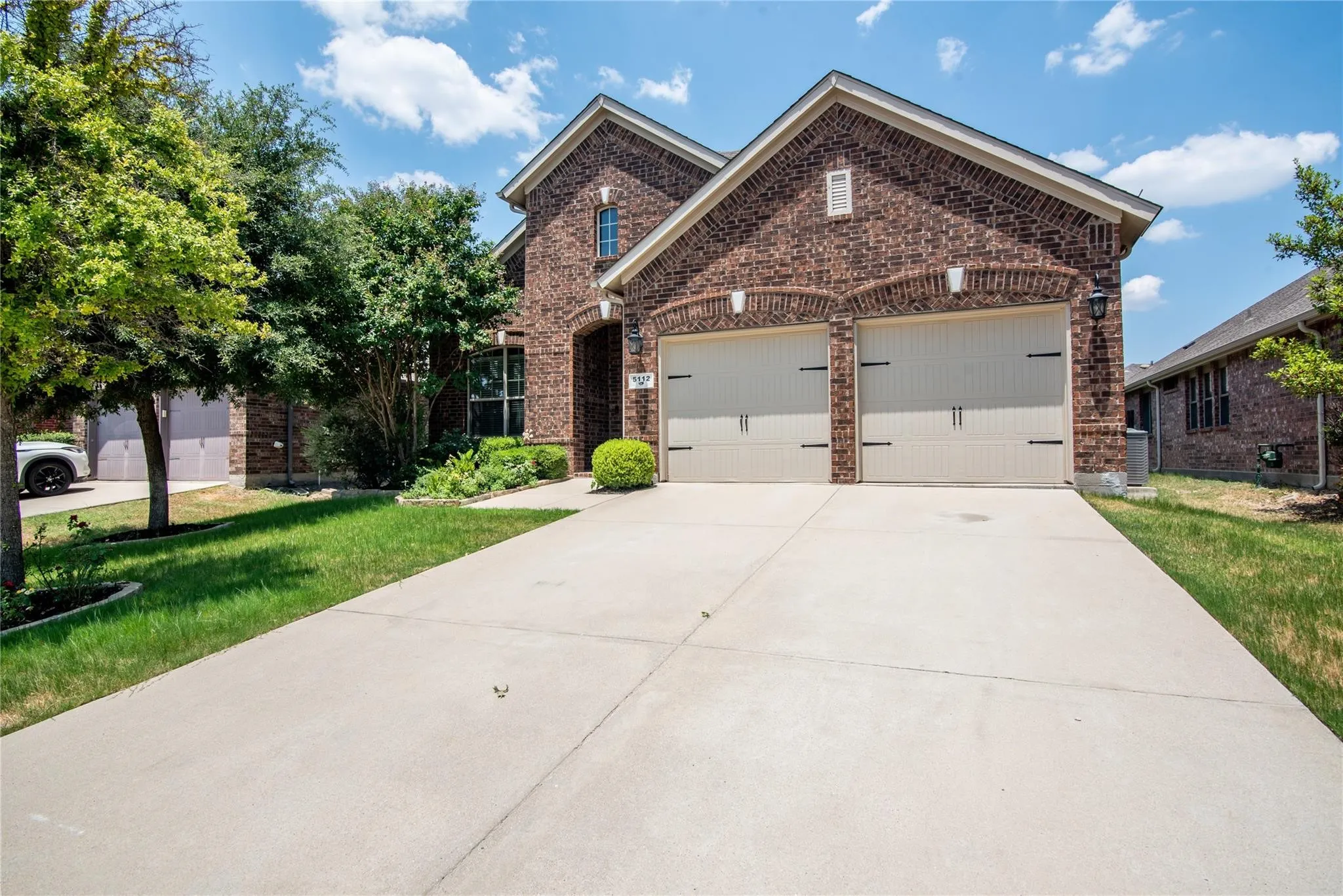 Traditional-style house with a front lawn, concrete driveway, an attached garage, and brick siding