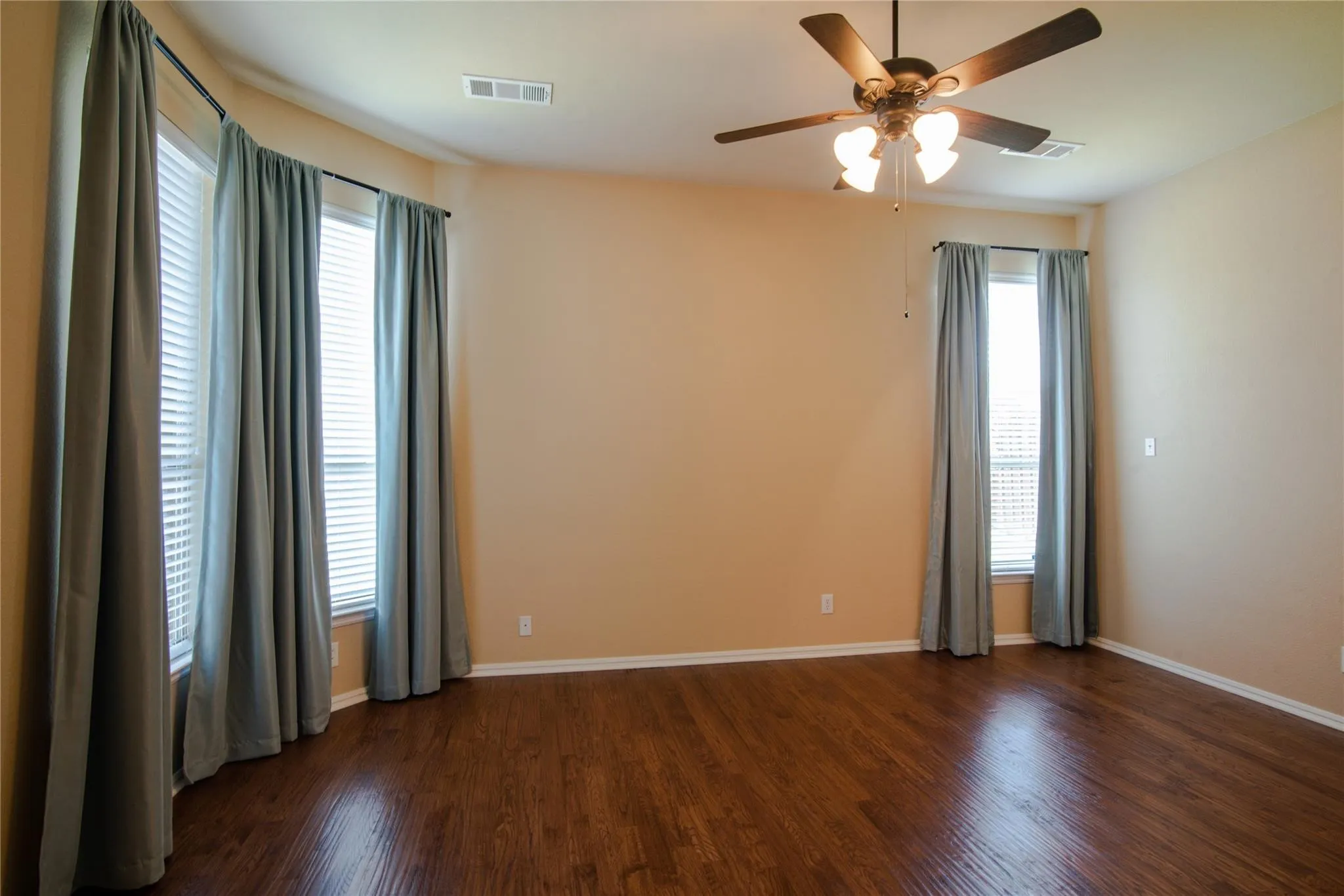 Empty room featuring dark wood-type flooring and a ceiling fan