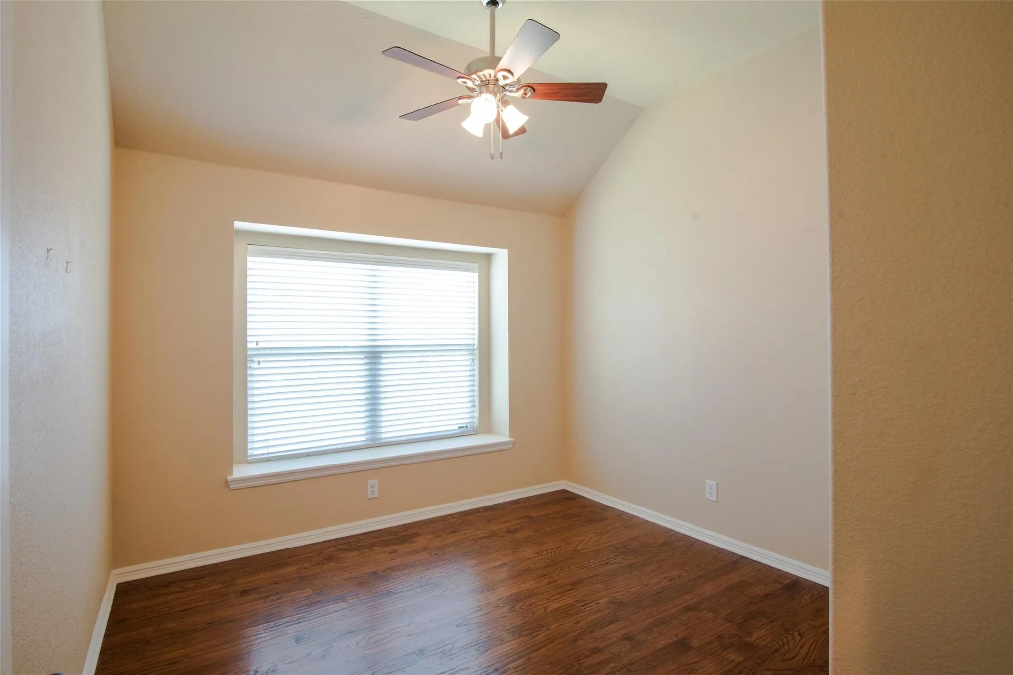 Spare room featuring dark wood-style flooring, ceiling fan, and vaulted ceiling