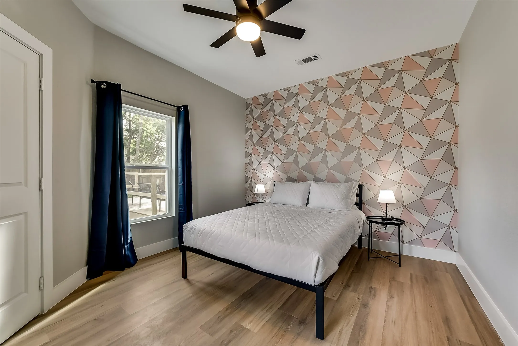 Bedroom with visible vents, baseboards, lofted ceiling, and an accent wall