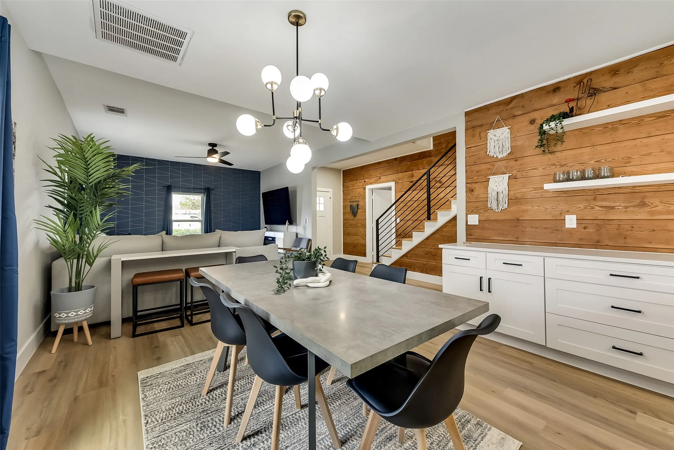 Dining area featuring stairs, light wood-type flooring, visible vents, and wood walls