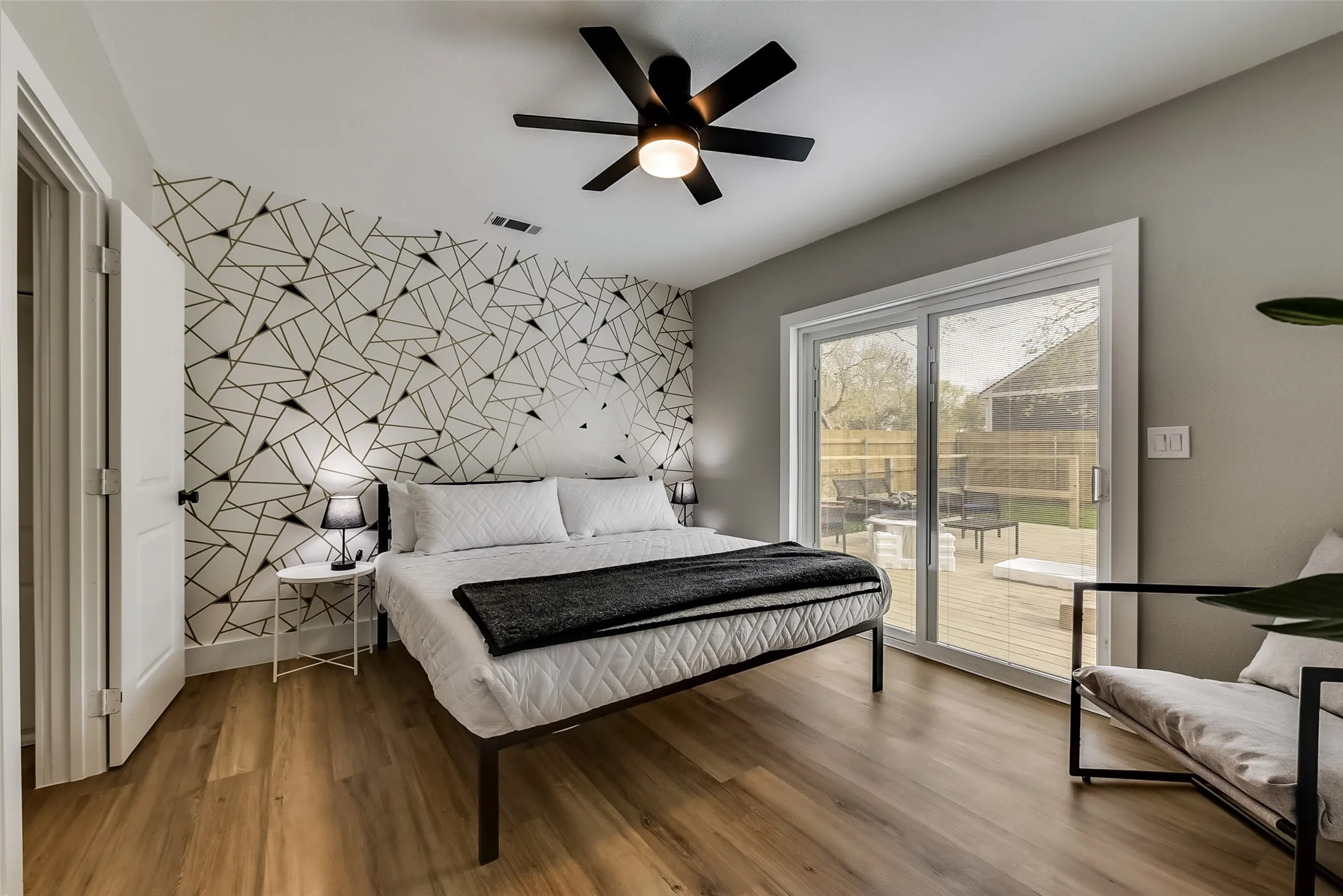Bedroom featuring wood finished floors, visible vents, an accent wall, a ceiling fan, and access to exterior