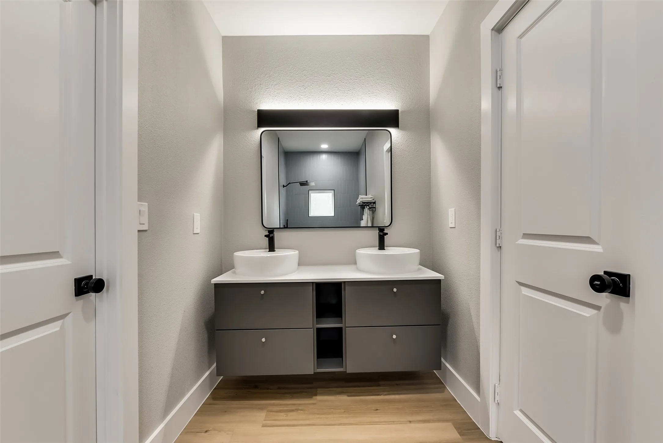 Bathroom featuring double vanity, wood finished floors, baseboards, and a sink