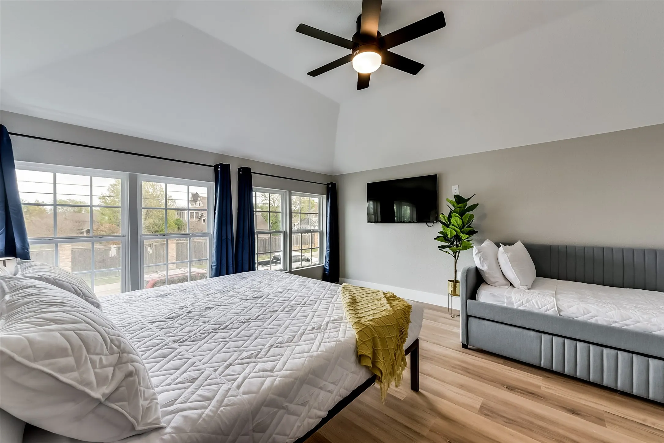 Bedroom featuring baseboards, light wood-style floors, high vaulted ceiling, and a ceiling fan