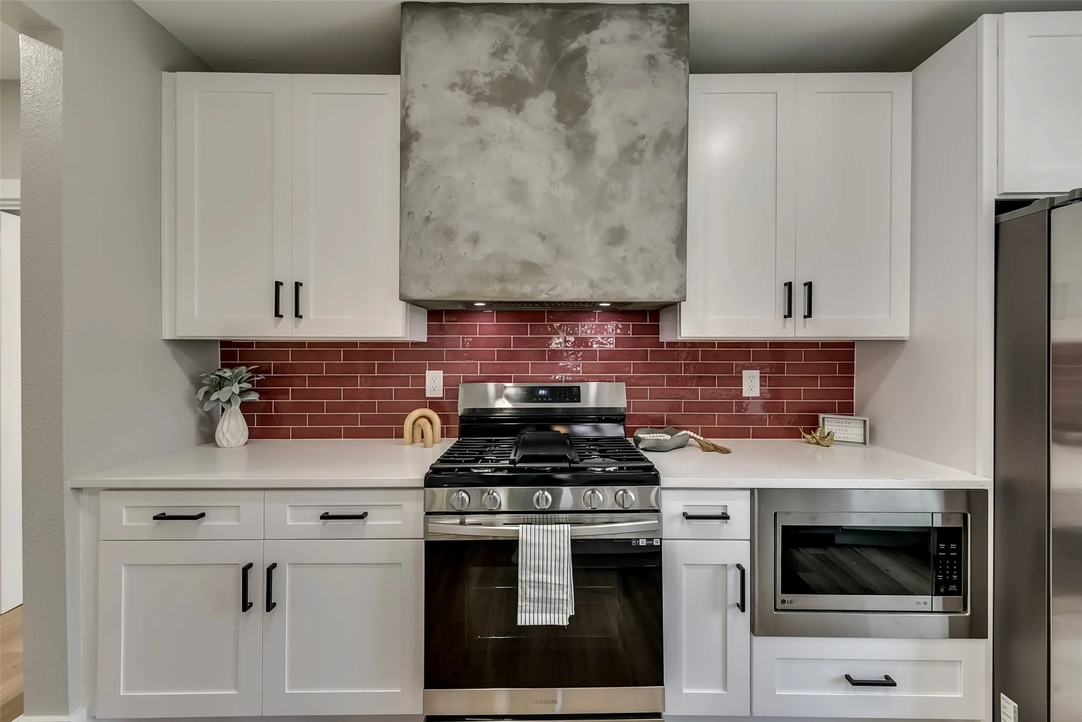 Kitchen with white cabinetry, light countertops, tasteful backsplash, and appliances with stainless steel finishes