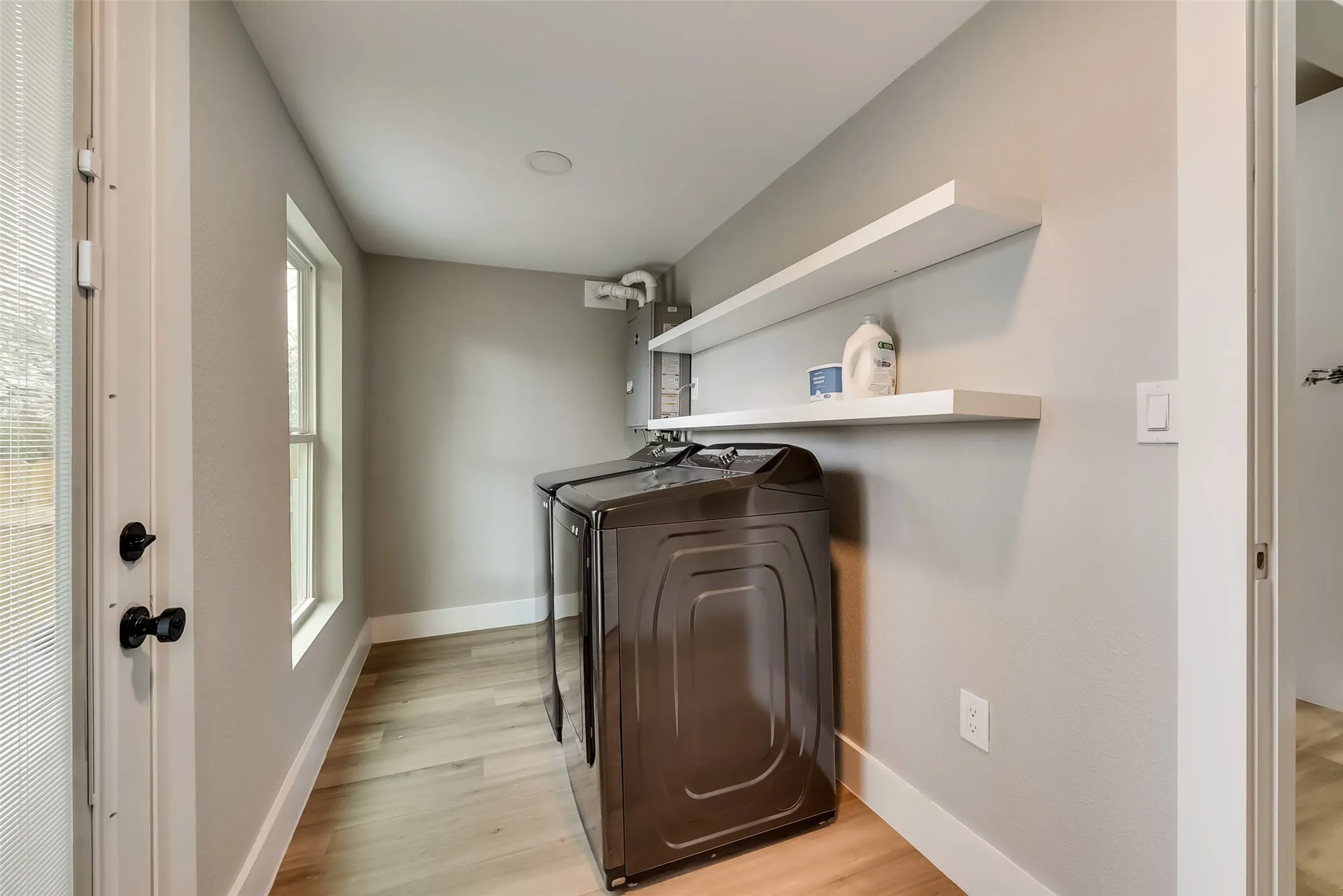 Washroom featuring baseboards, laundry area, washer and dryer, and light wood-style floors