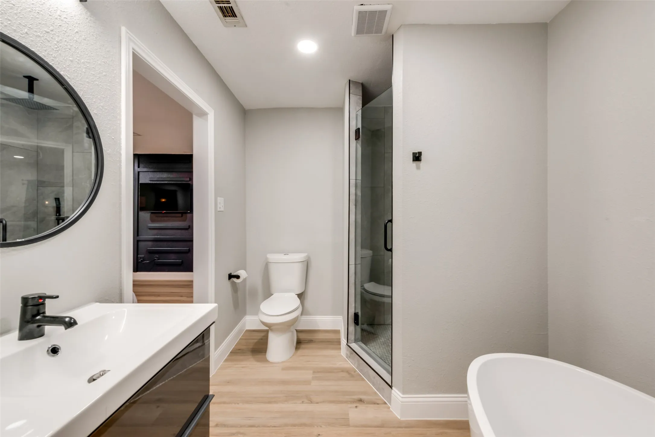 Full bathroom featuring a stall shower, wood finished floors, a freestanding tub, and vanity