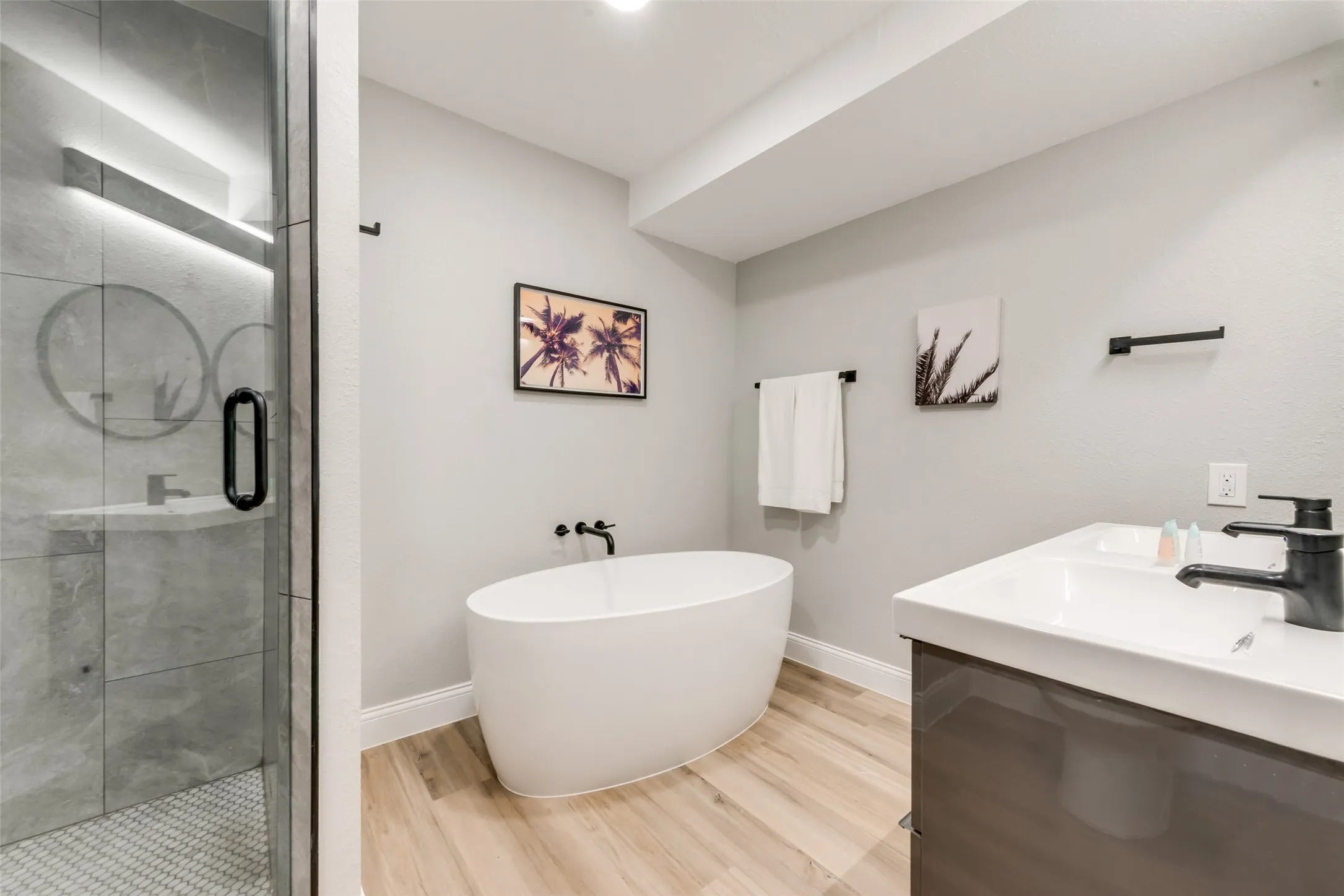 Bathroom with wood finished floors, a stall shower, and a freestanding tub