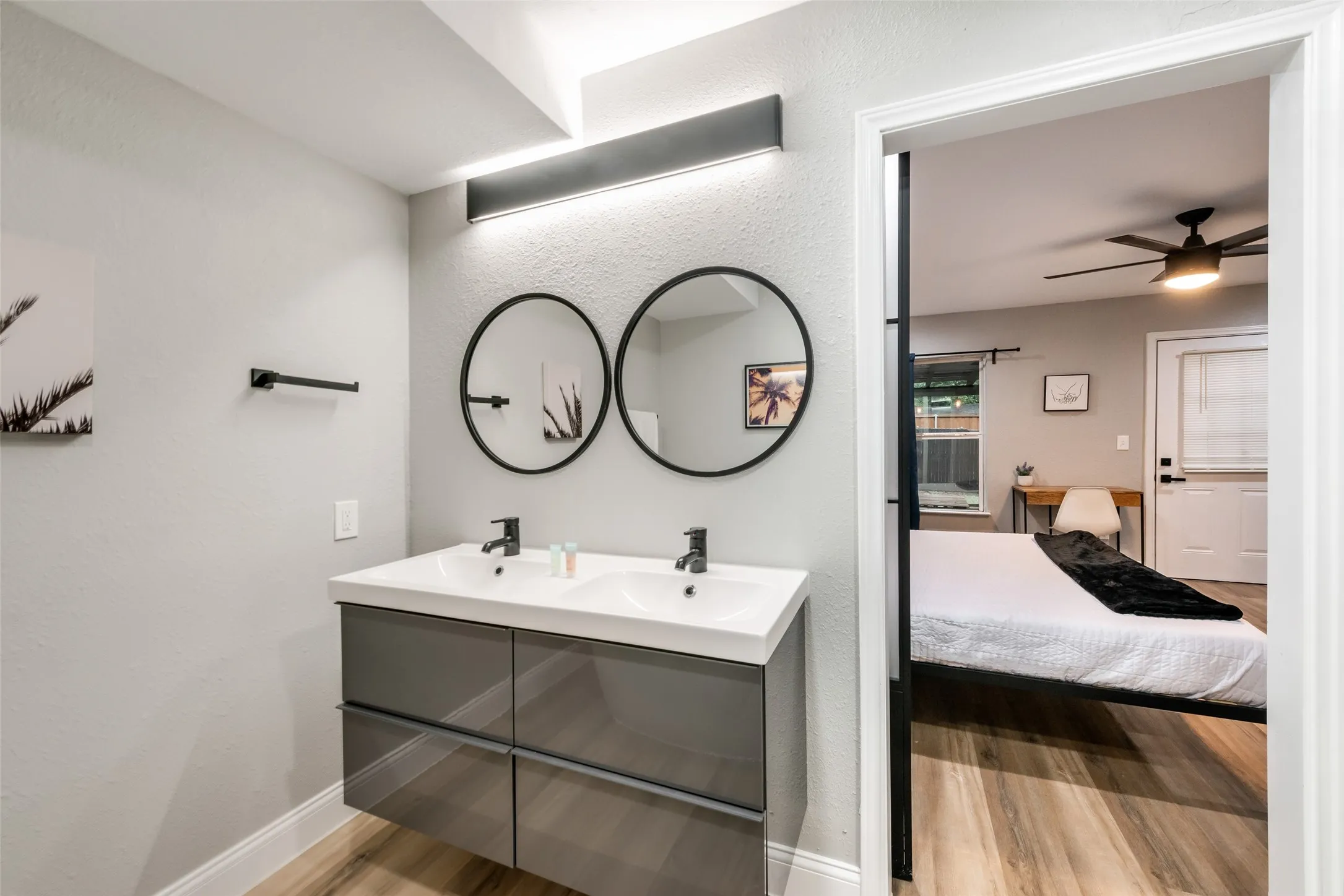 Full bath with wood finished floors, a textured wall, double vanity, and a ceiling fan