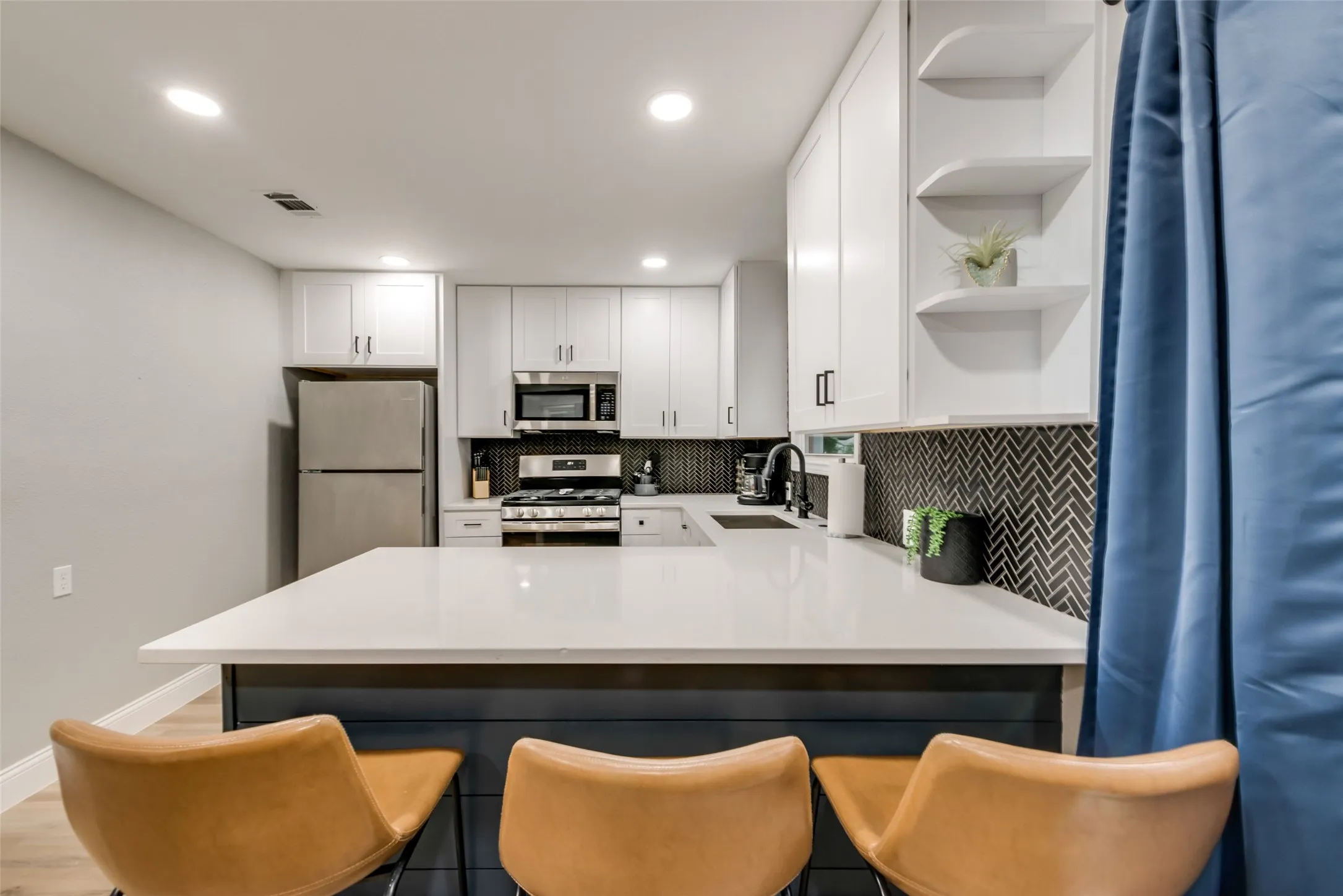 Kitchen with open shelves, decorative backsplash, appliances with stainless steel finishes, a peninsula, and white cabinetry