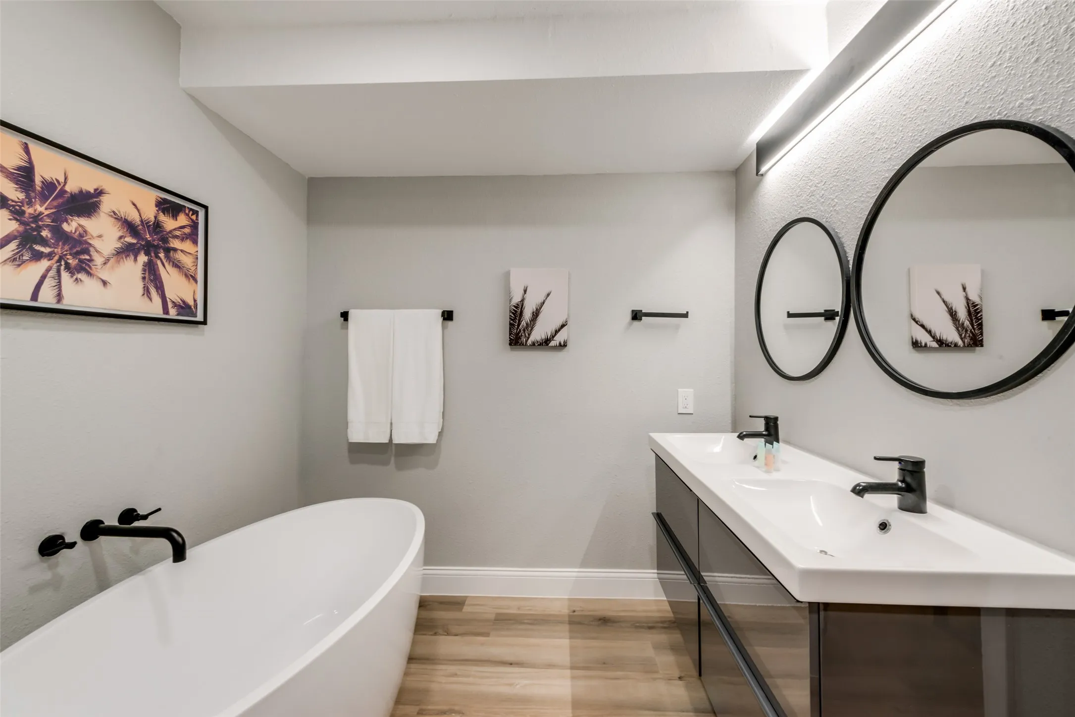 Full bath with wood finished floors, a soaking tub, and double vanity