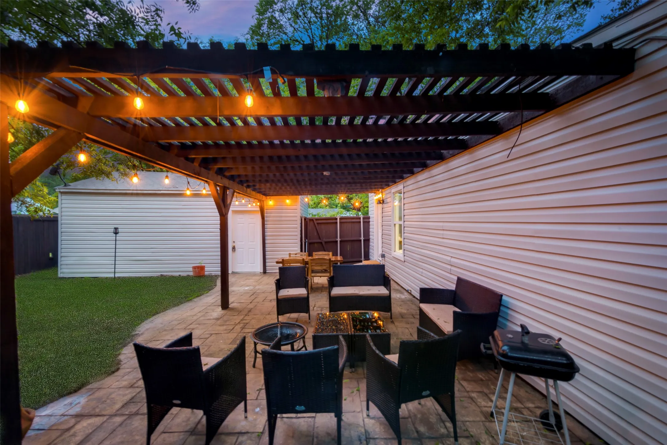 Patio terrace at dusk featuring an outdoor living space, area for grilling, a fenced backyard, a patio area, and an outdoor structure