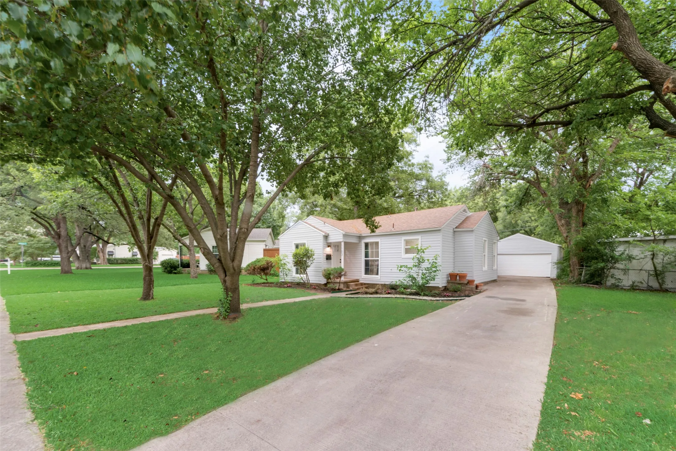 Ranch-style home with a detached garage, an outbuilding, and a front lawn
