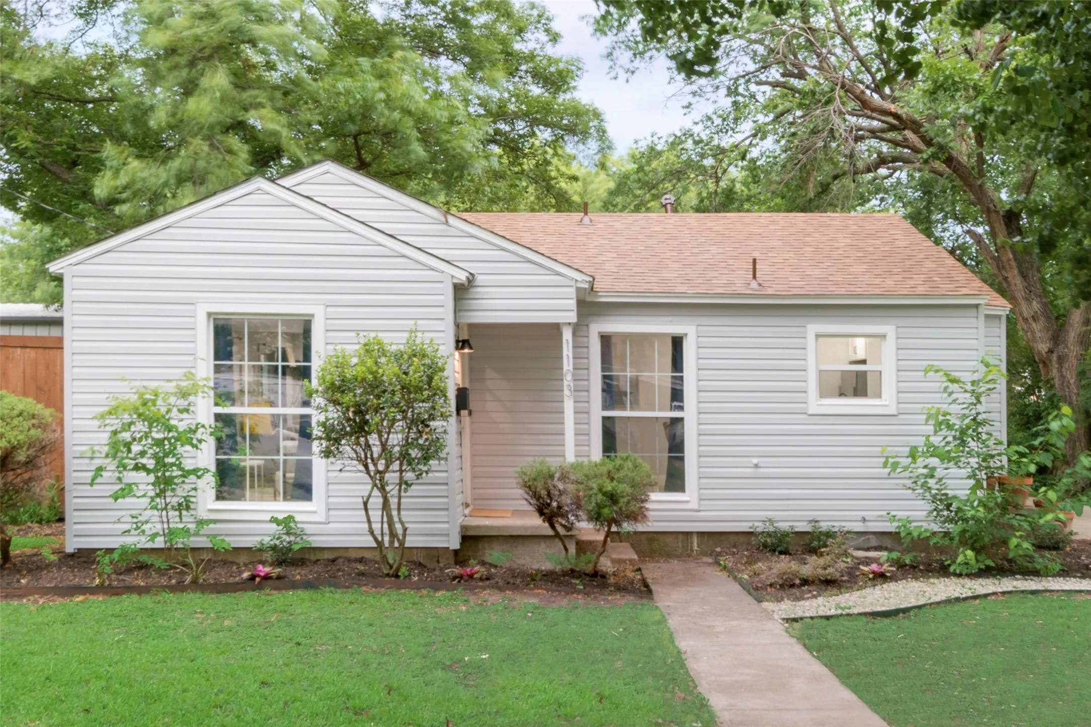 View of front facade with roof with shingles and a front yard