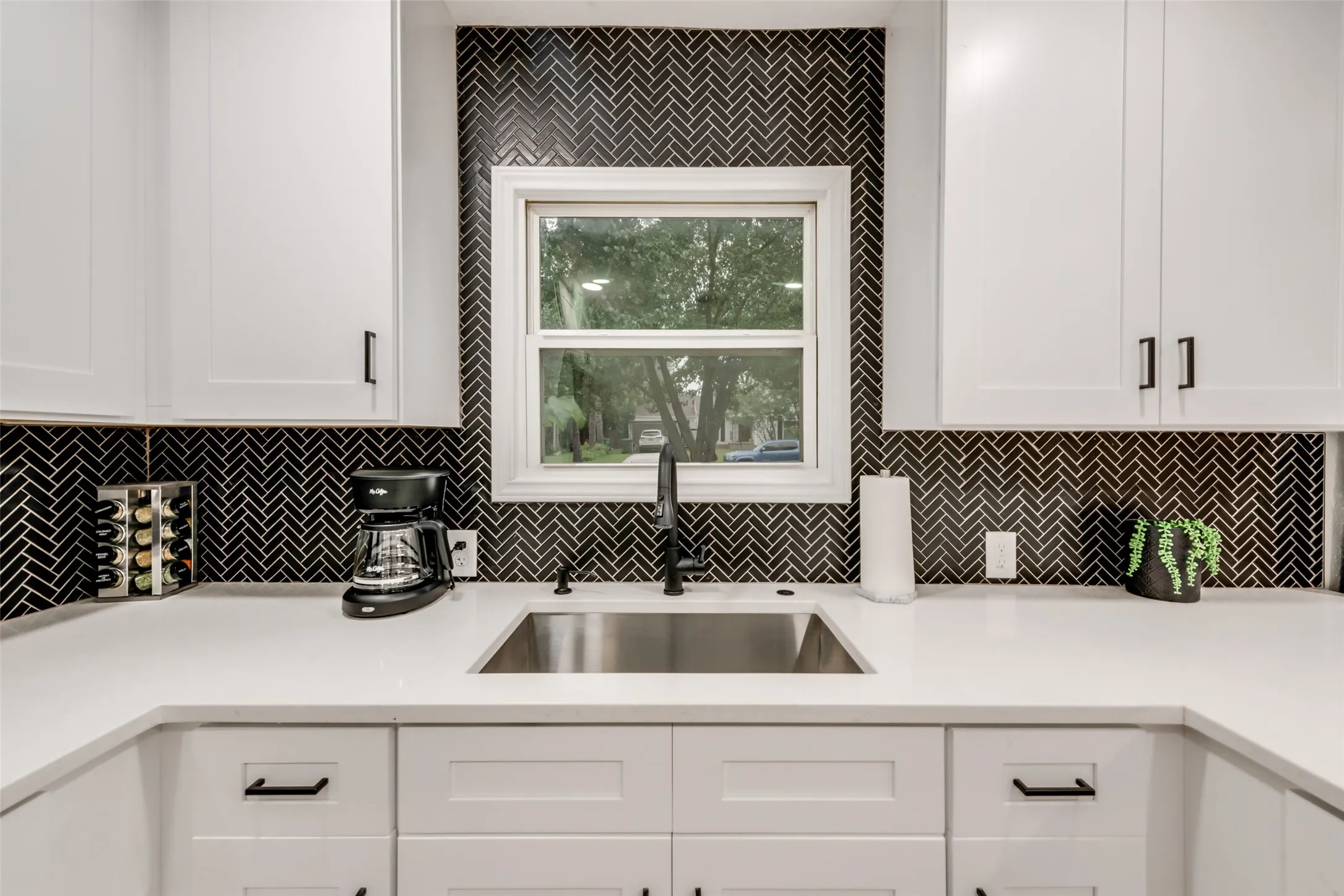 Kitchen with white cabinets, light countertops, and backsplash