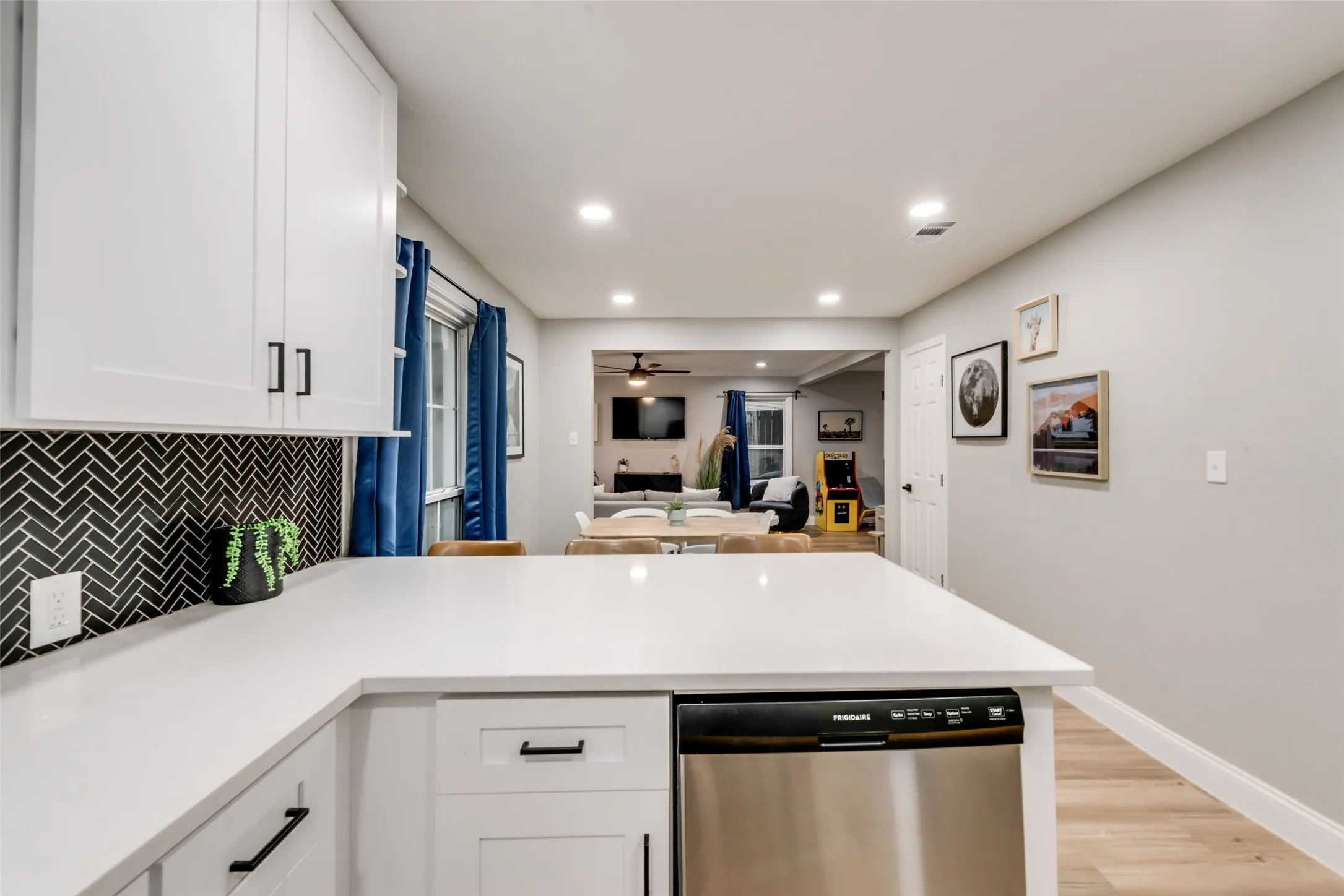 Kitchen featuring a peninsula, stainless steel dishwasher, white cabinets, backsplash, and recessed lighting
