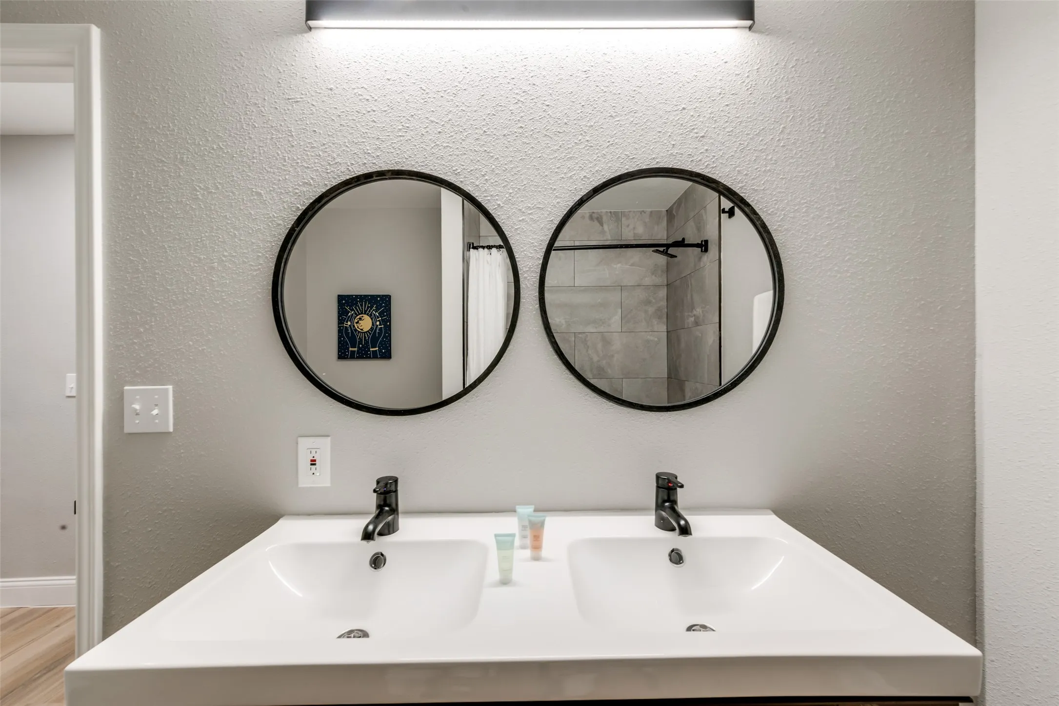 Full bath featuring a textured wall, double vanity, and a shower with shower curtain