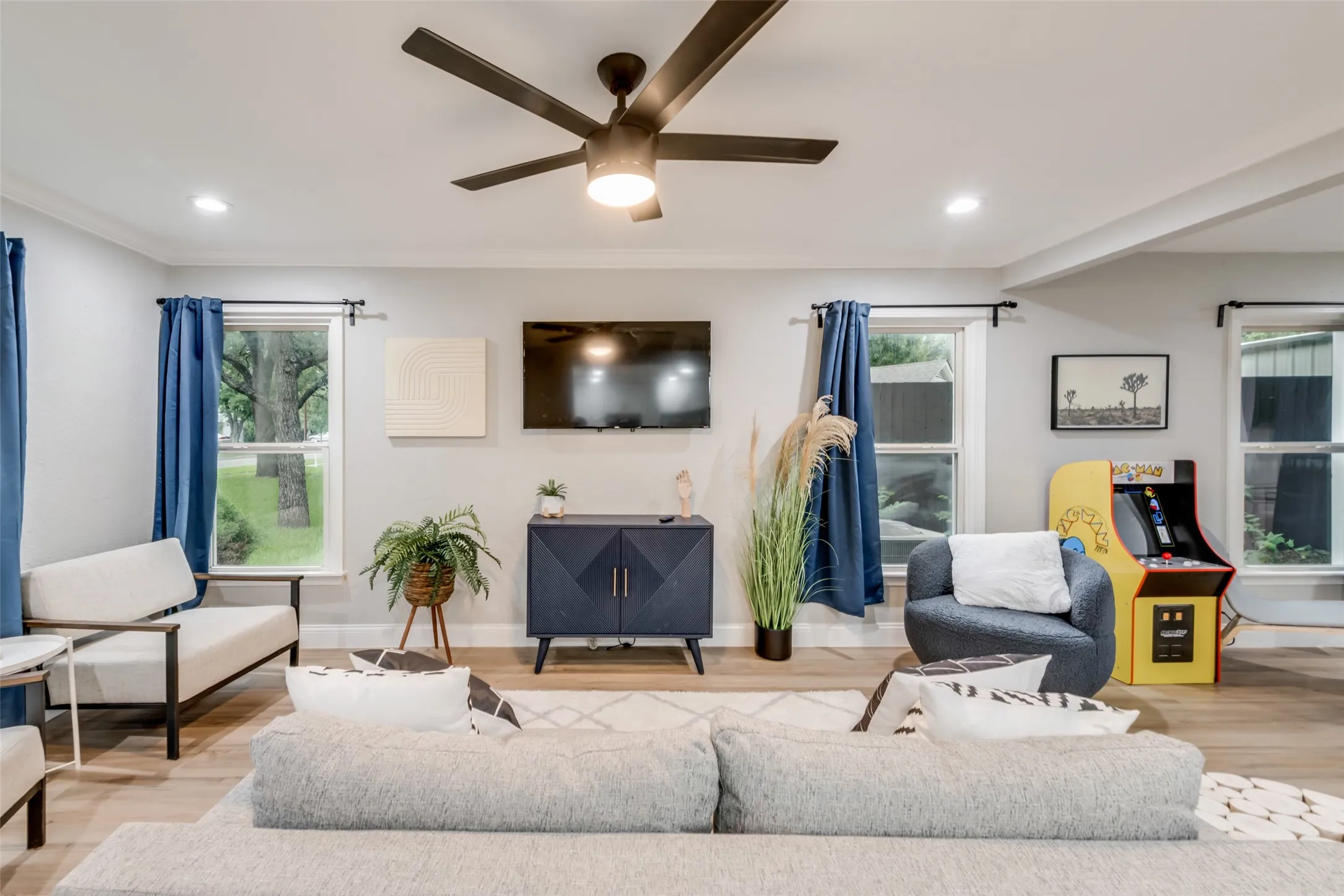 Living room featuring wood finished floors, plenty of natural light, a ceiling fan, recessed lighting, and crown molding
