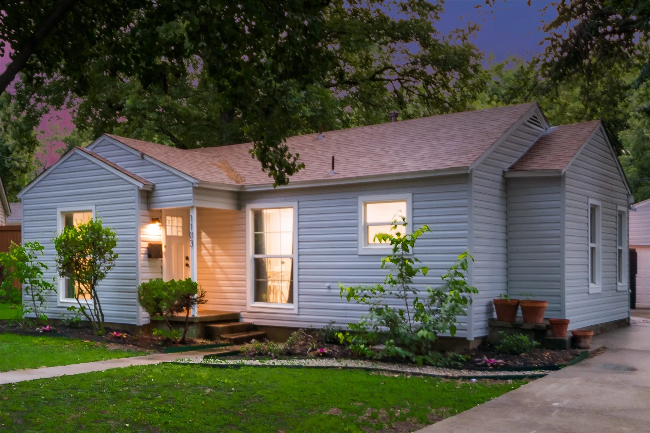 View of front of home with a shingled roof, a yard, and a garage