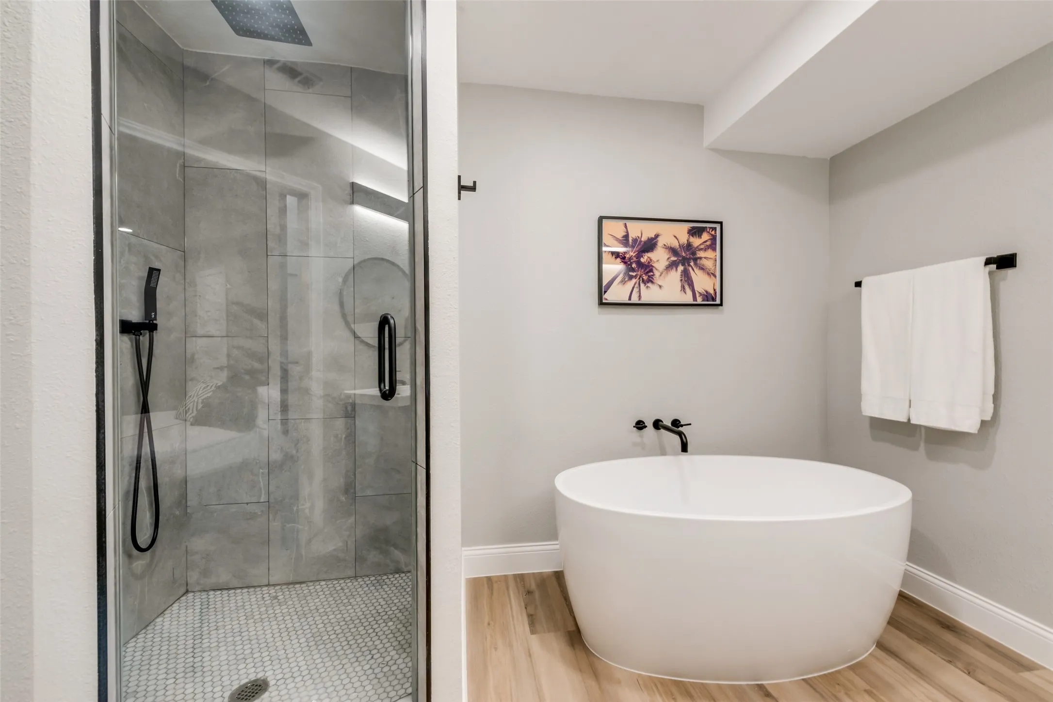 Bathroom featuring a stall shower, wood finished floors, and a freestanding bath