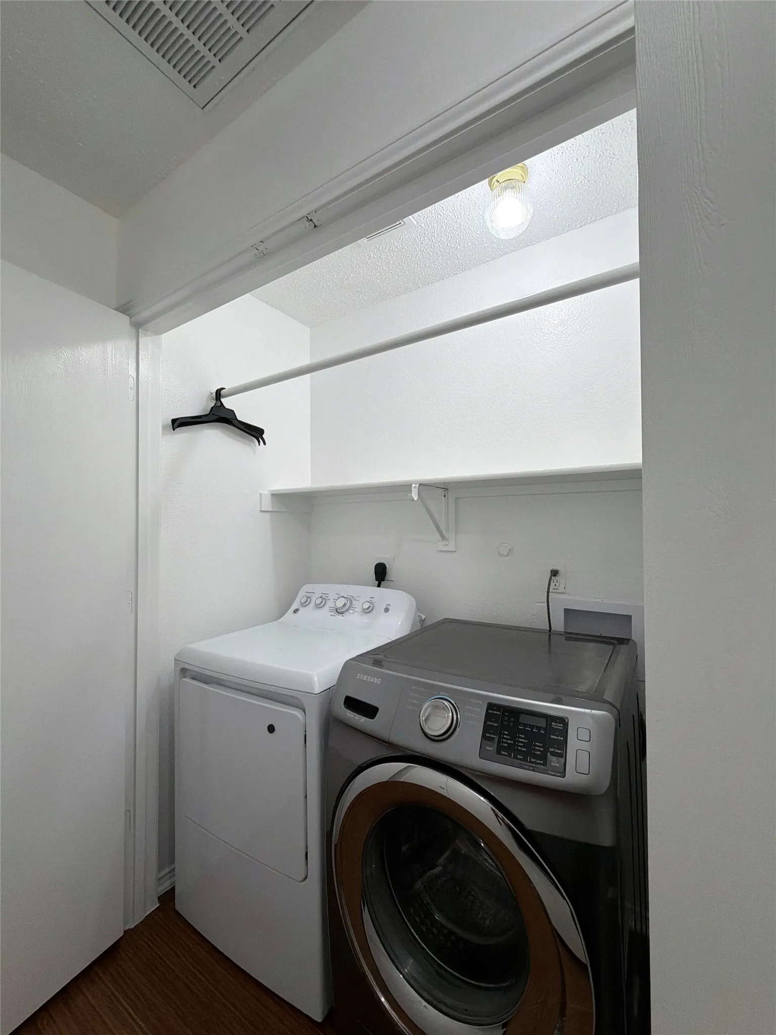 Laundry area featuring washer and clothes dryer, dark wood-style flooring, and a textured ceiling