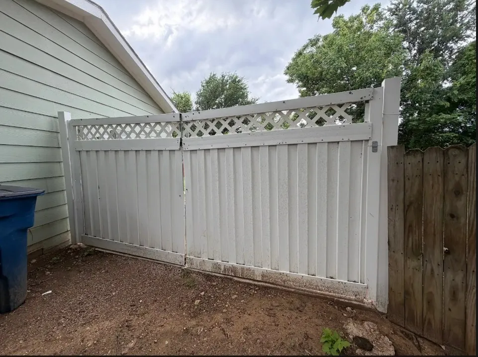 White privacy fence with lattice top, double gate entry, and adjacent wood fencing
