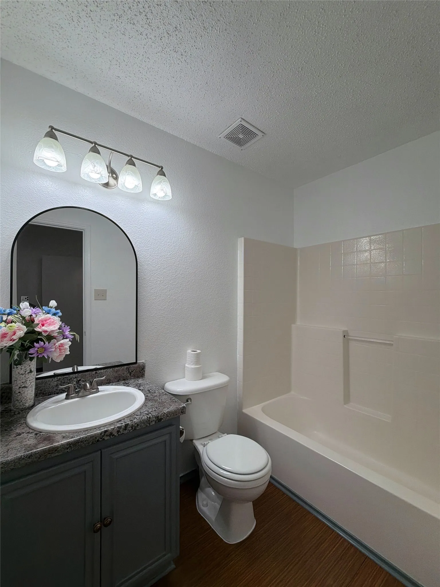 Primary Full bathroom featuring vanity, a textured ceiling, dark wood finished floors, and shower / washtub combination
