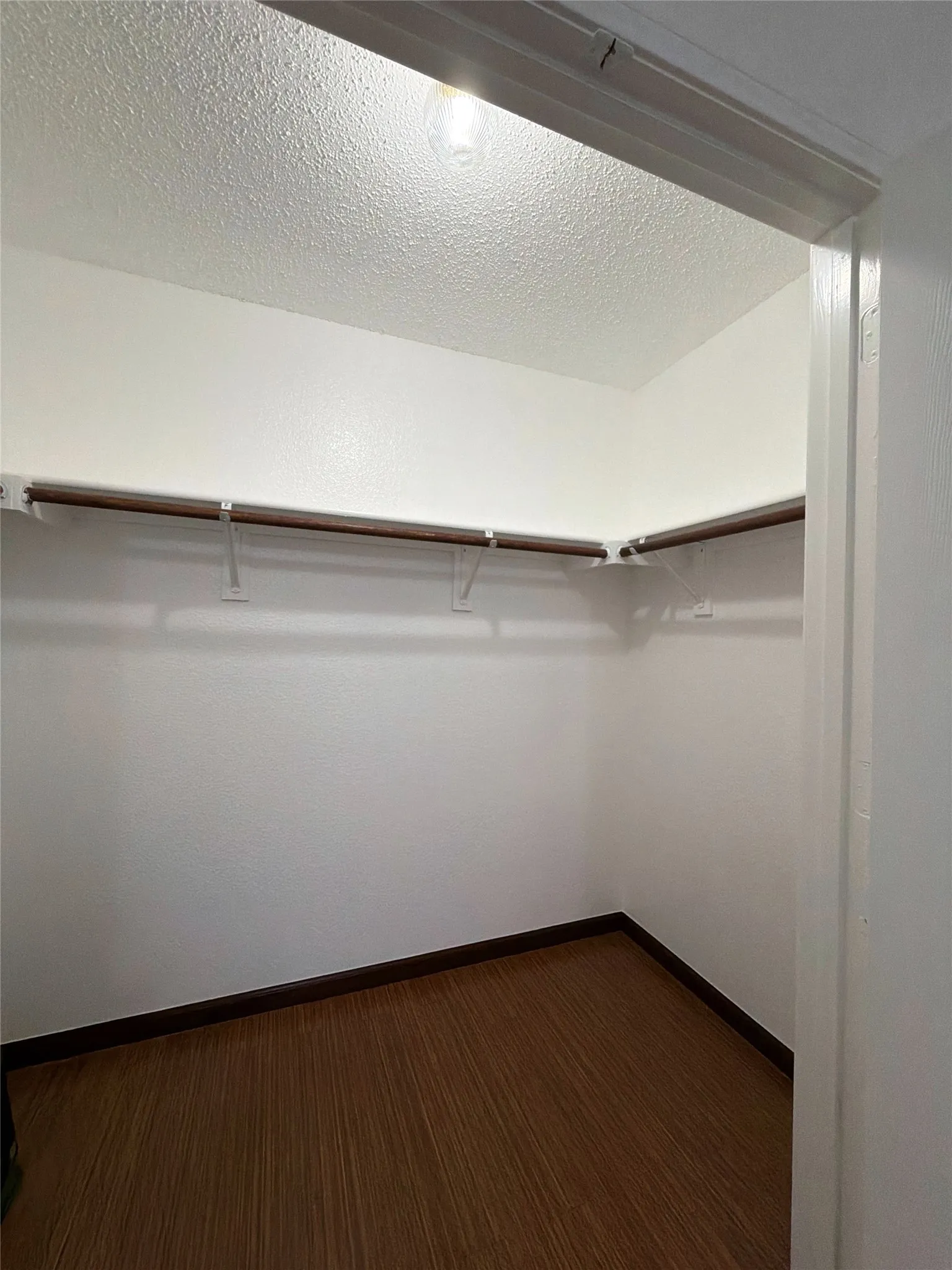 Walk in closet featuring dark wood-style flooring