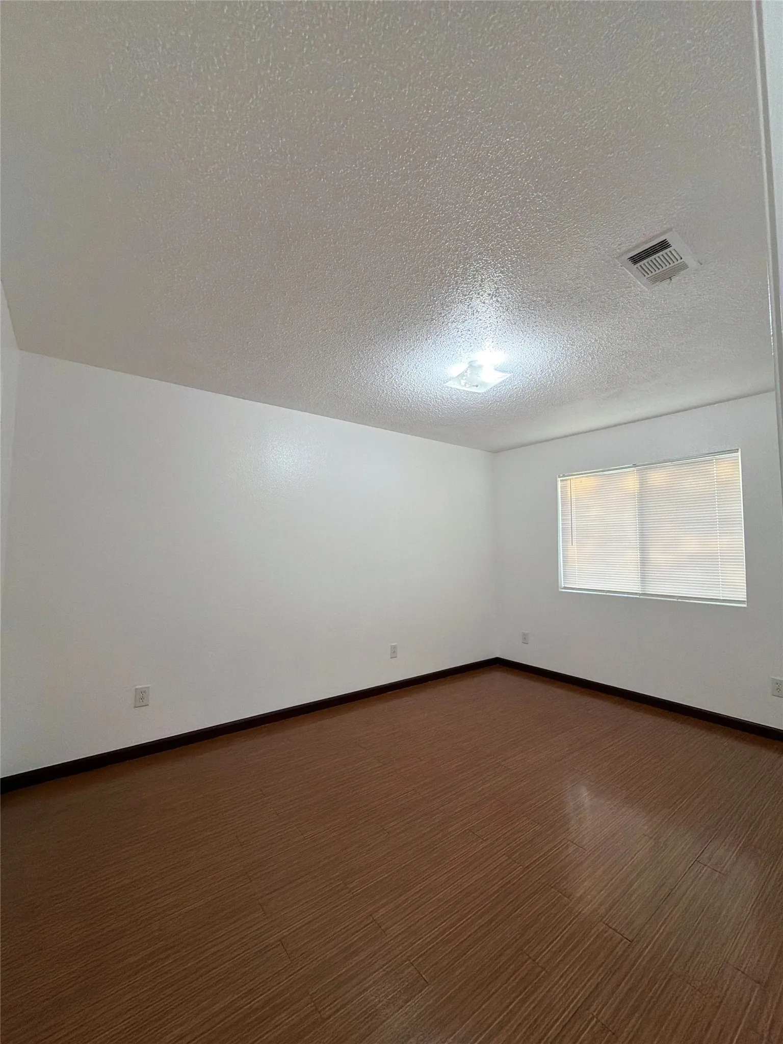 Unfurnished room with a textured ceiling and wood finished floors