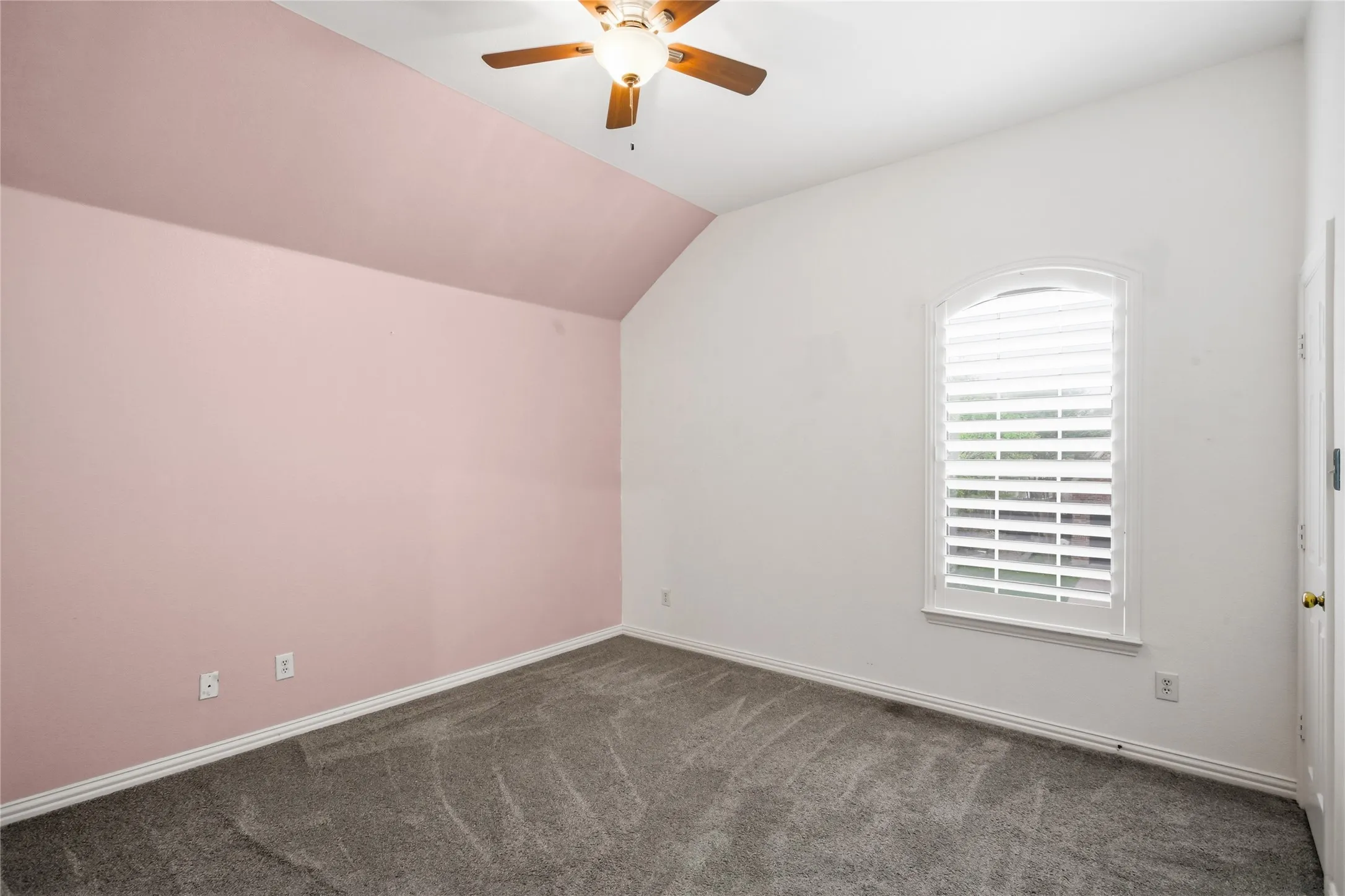 Good size secondary bedroom with vaulted ceilings and pretty blush colored accent wall.