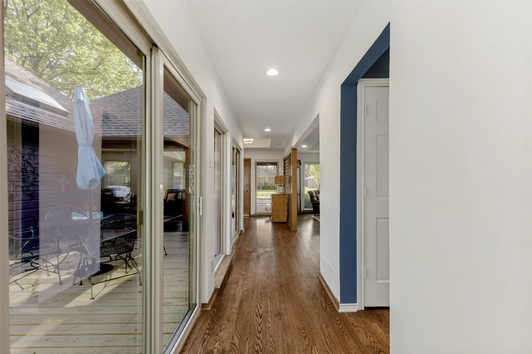 View of hallway with hardwood flooring and access to the interior courtyard with decking so you can enjoy a glass of wine or morning cup of coffee