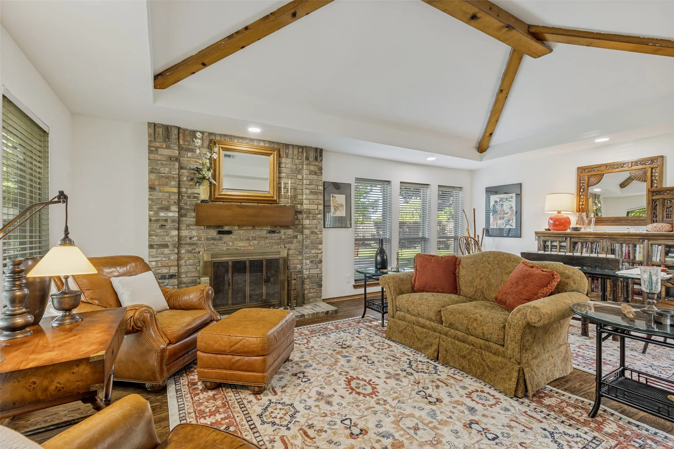 Formal Living and Dining Rooms open to one another and feature a wood-burning fireplace and vaulted ceiling