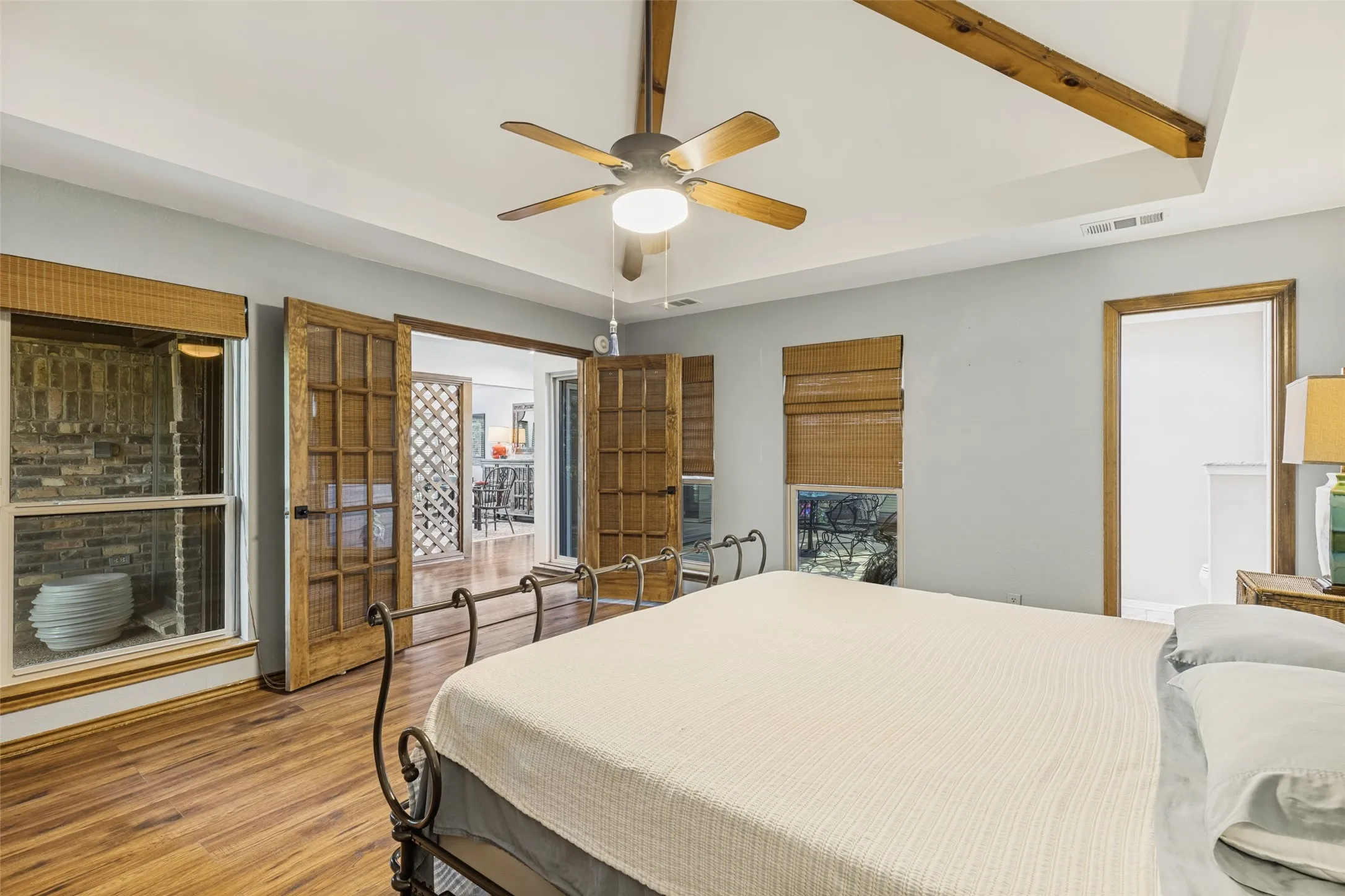 Another view of the Primary Bedroom with French Doors and ceiling fan and windows that overlook the interior courtyard