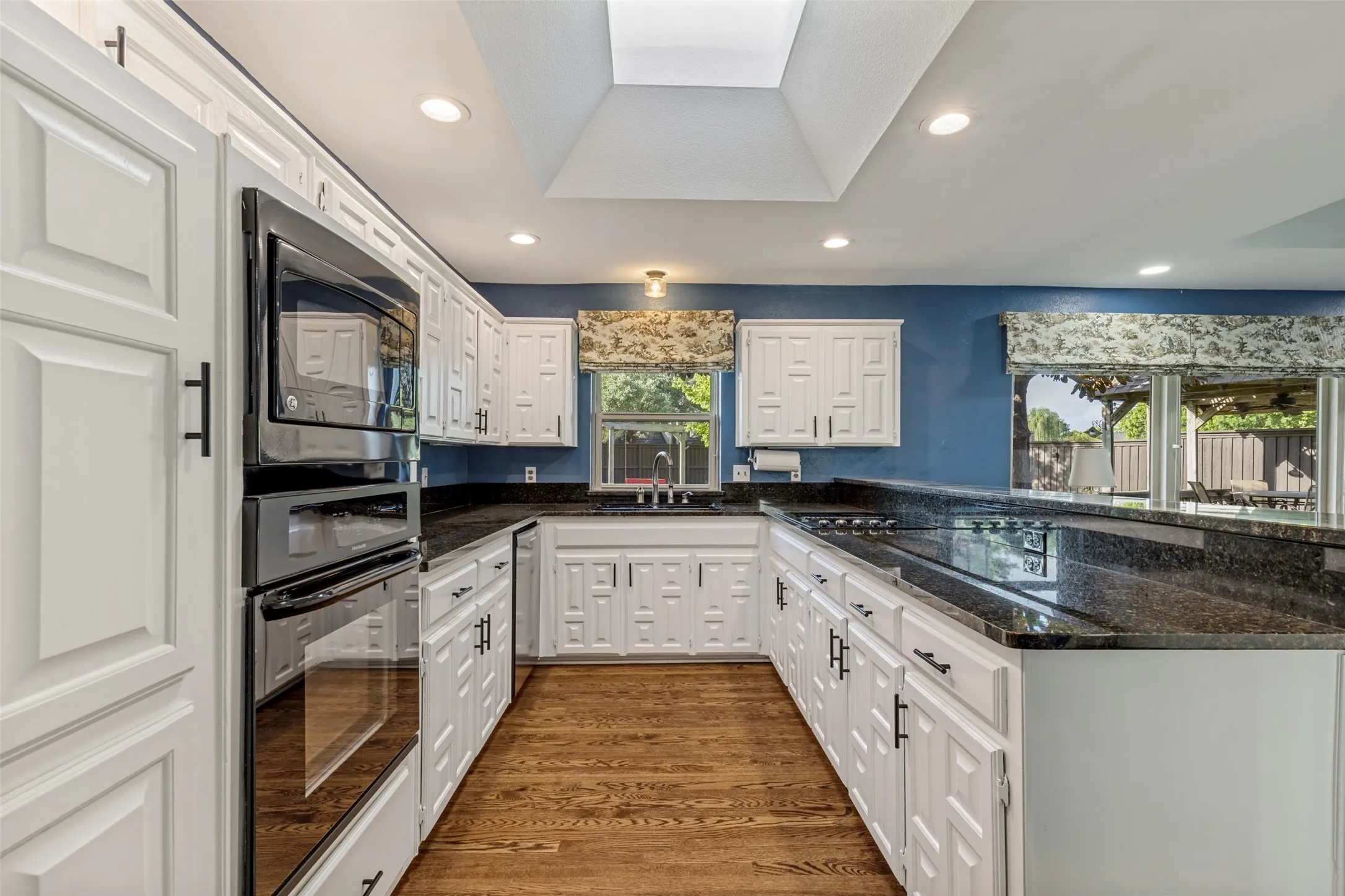Kitchen features granite counter tops, painted cabinetry, recessed lights, cooktop and built-in oven and microwave