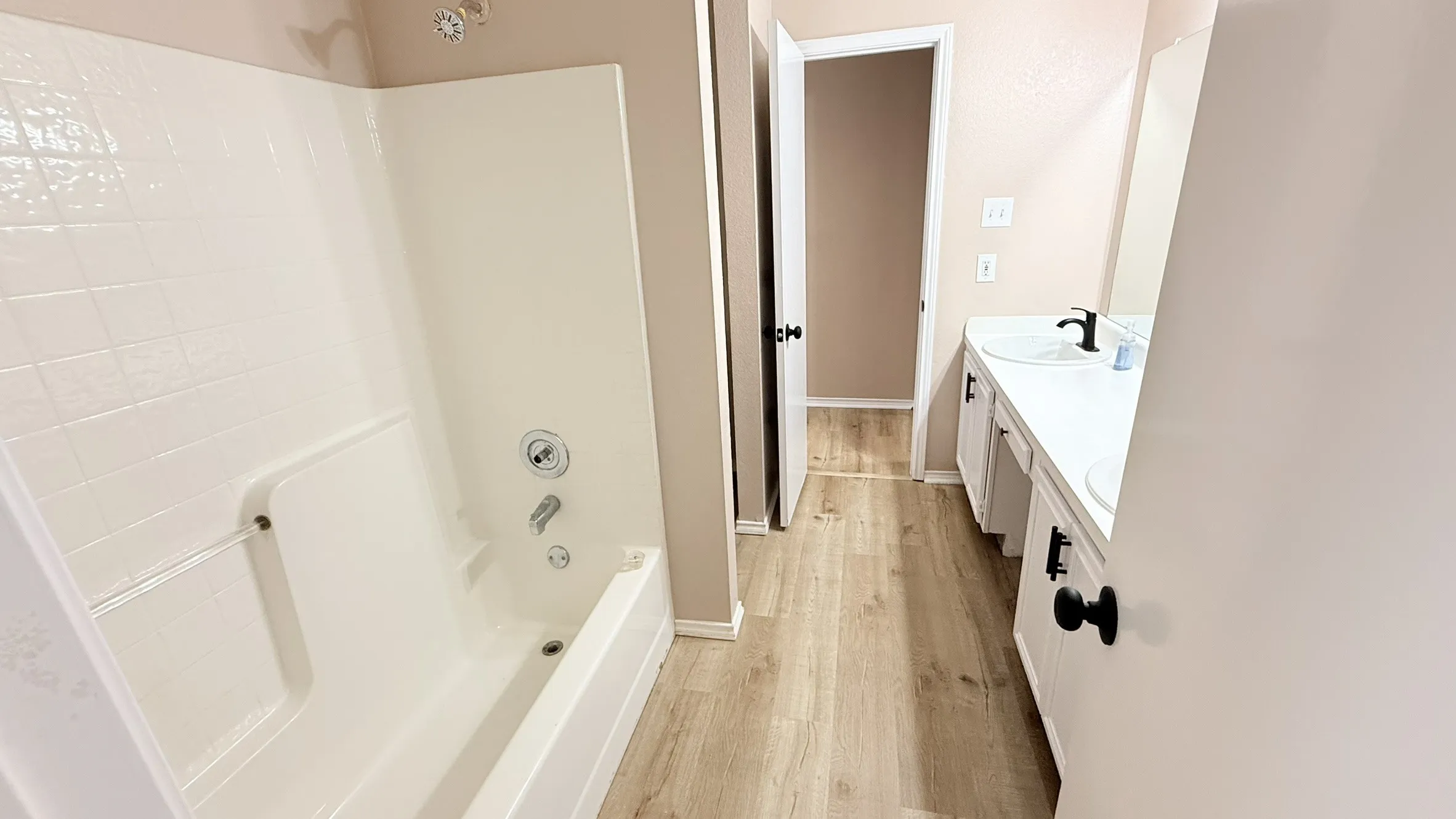 Bathroom featuring double vanity, light wood-style flooring, and washtub / shower combination