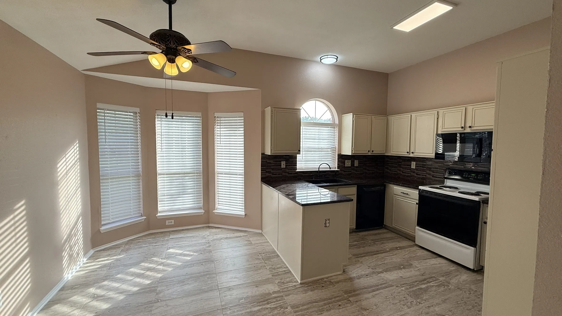 Kitchen featuring black appliances, a peninsula, backsplash, and ceiling fan