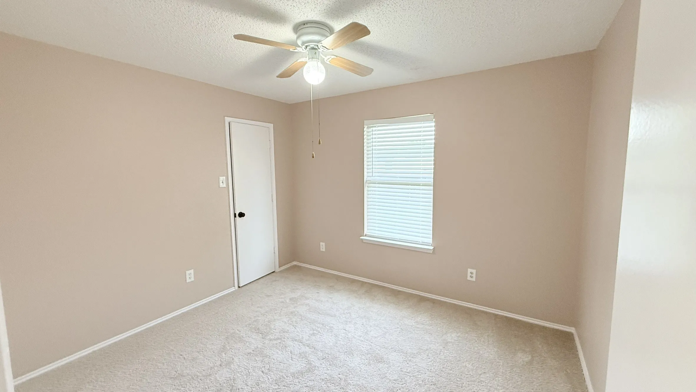 Carpeted empty room with a textured ceiling and ceiling fan