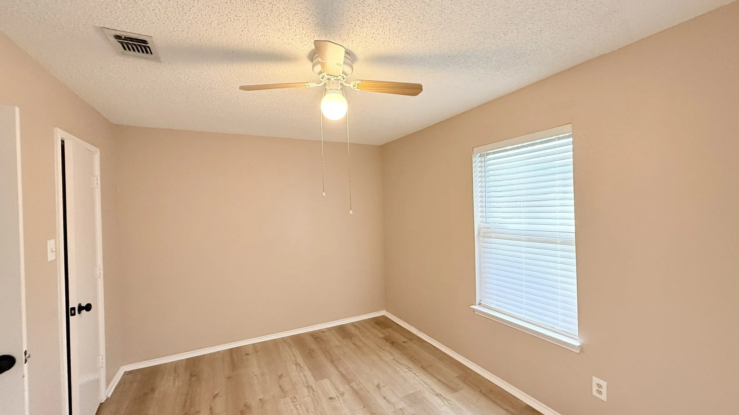 Spare room featuring a textured ceiling, light wood-type flooring, and ceiling fan
