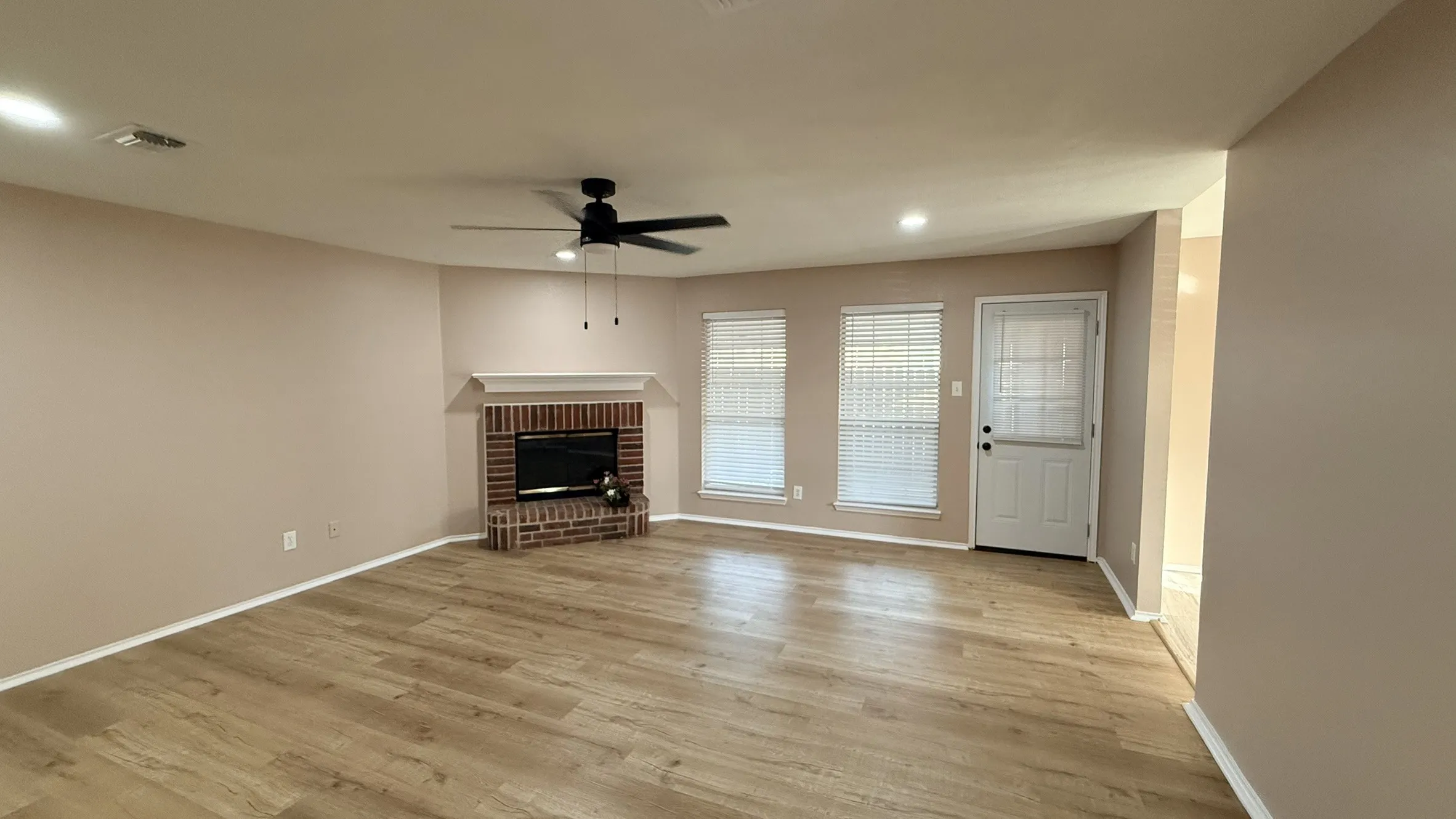 Unfurnished living room featuring a brick fireplace, ceiling fan, light wood-style floors, and recessed lighting