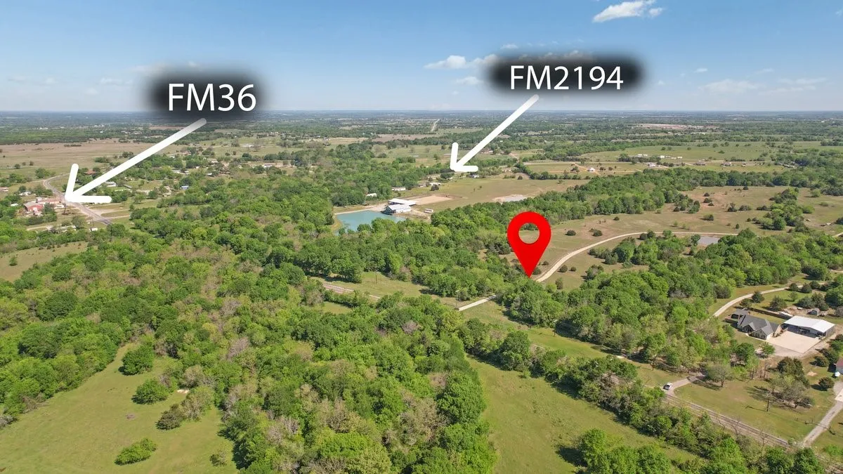 Aerial view showcasing the expansive rural landscape with green foliage and a body of water